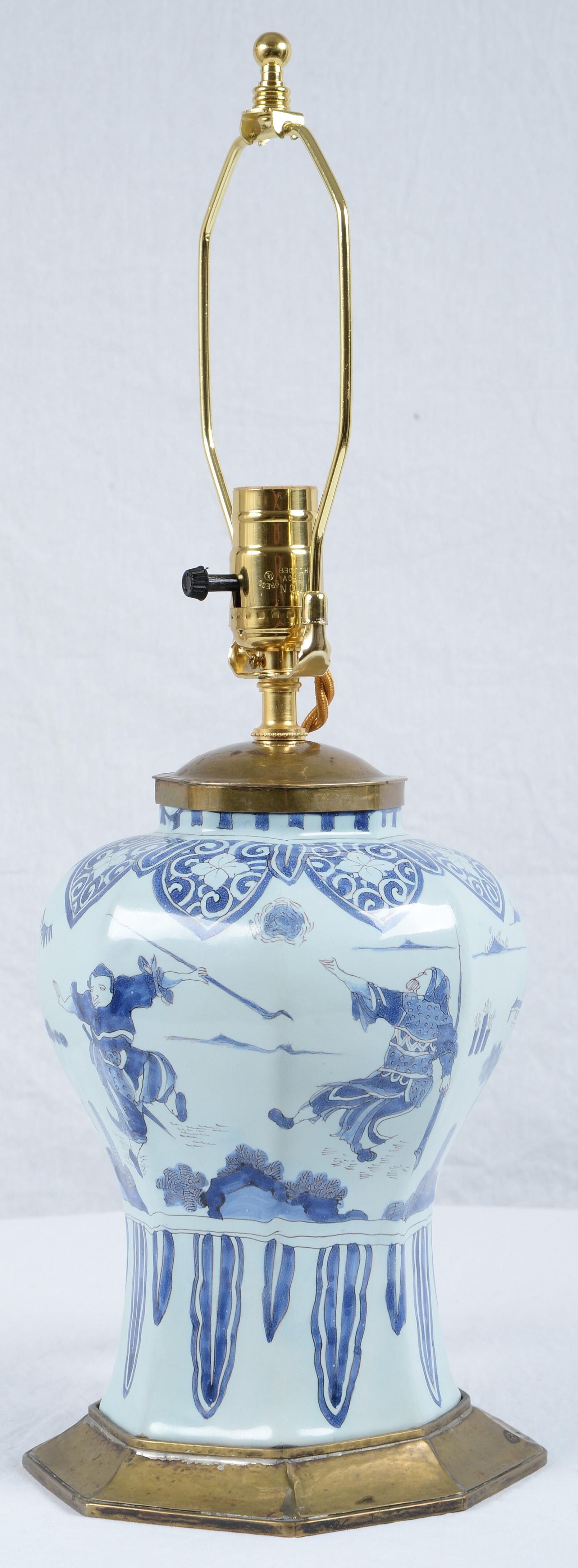 Achteckige Fayence-Vase aus Delft aus dem 17. Jahrhundert, in Messing gefasst und mit einem Chinoiserie-Dekor aus kämpfenden Kriegern und exotischen Landschaften verziert. Die hier angegebenen Maße sind die der Vase mit Beschlägen und Lampenschirm.