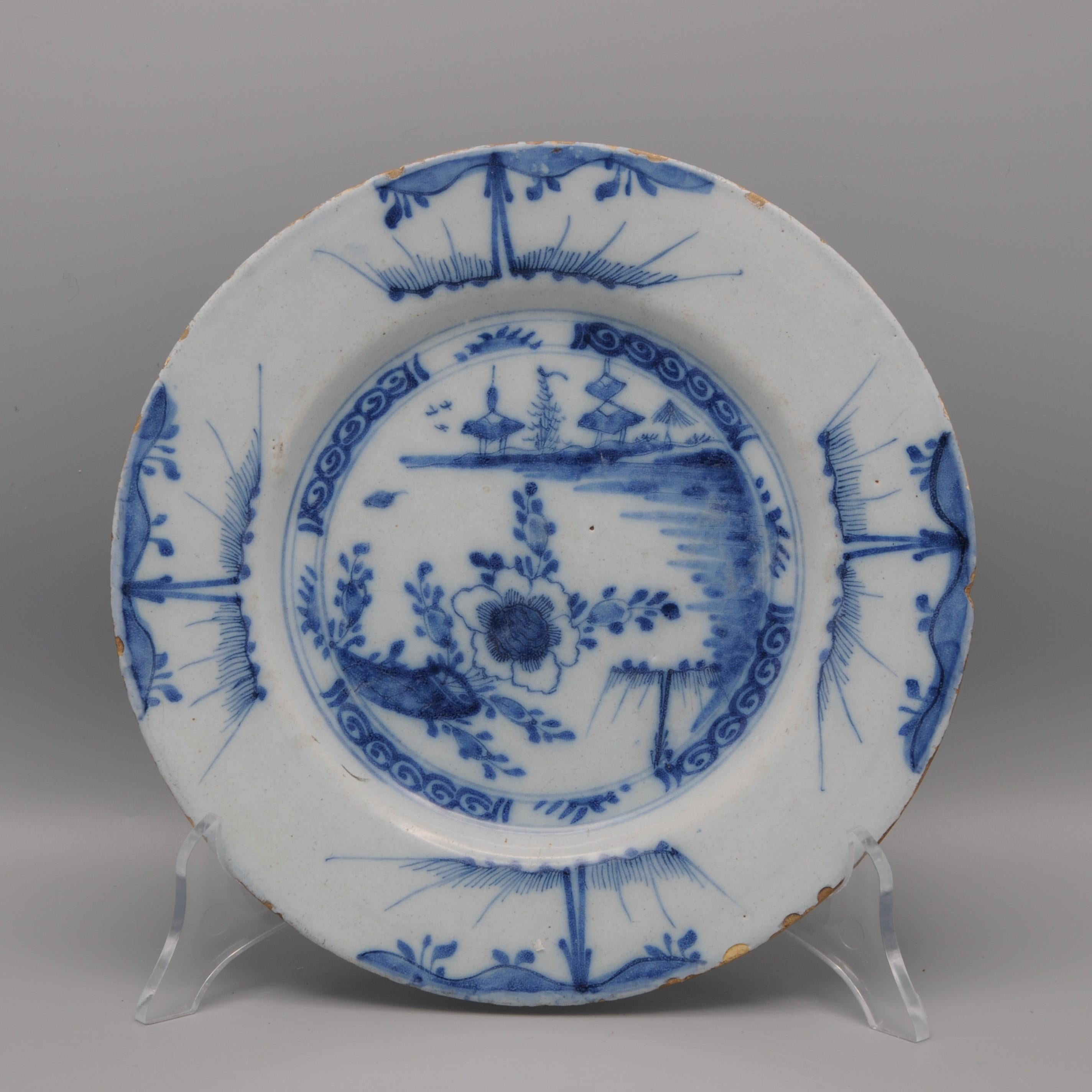 Mid 18th century Blue Delftware plate with chinoiserie decoration of a flowers and pagodes in the background. Qianlong style
Unmarked

Good condition; some chipping and usual wear to the rim. Larger chip to the back but not visible on the front.
