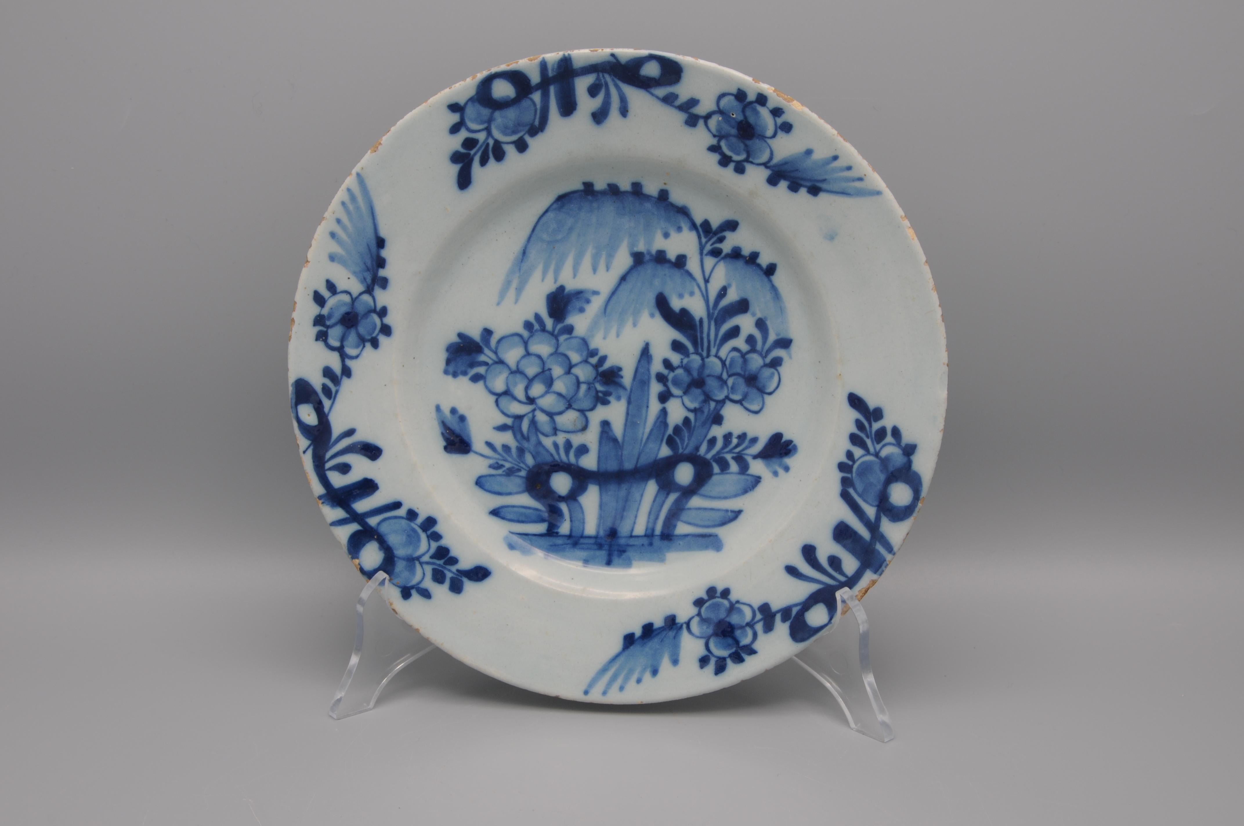 Plato chinoiserie azul de Delft que representa un paisaje oriental con flores, un arbusto y un sauce. Los bordes decorados con tres manojos de ramitas de flores y follaje. 


Estado: algunos arañazos y desgaste. Algunos desconchones en el borde.