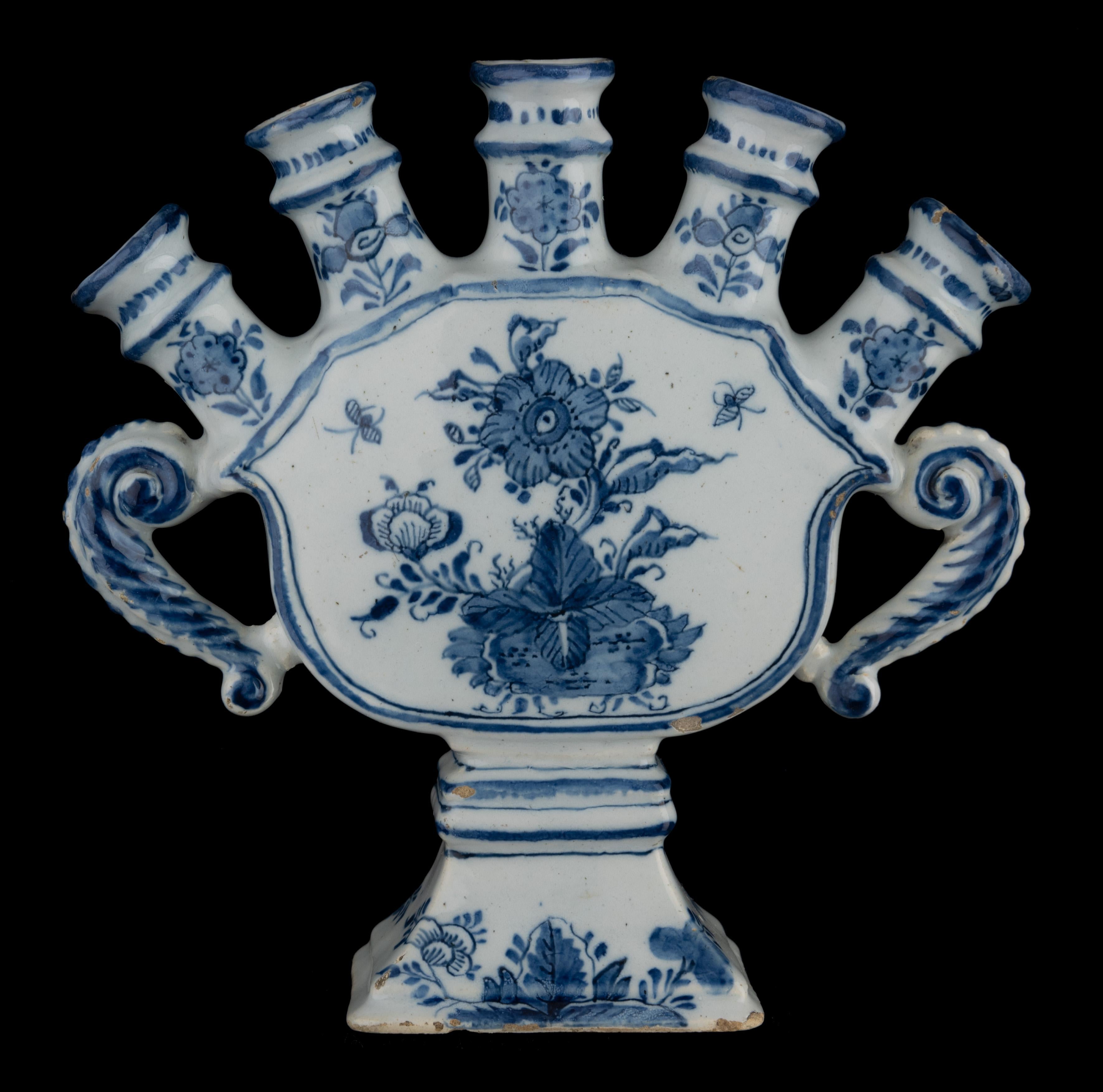Delft Blau-weiße Blumenvase mit Tüllen Delft, 1720-1730 

Die Blumenvase des Quintel-Modells ist schalenförmig und wird von fünf kurzen, verdickten Hälsen gekrönt, die eine fächerförmige Reihe von Ausgüssen bilden. Die Blumenvase steht auf einem