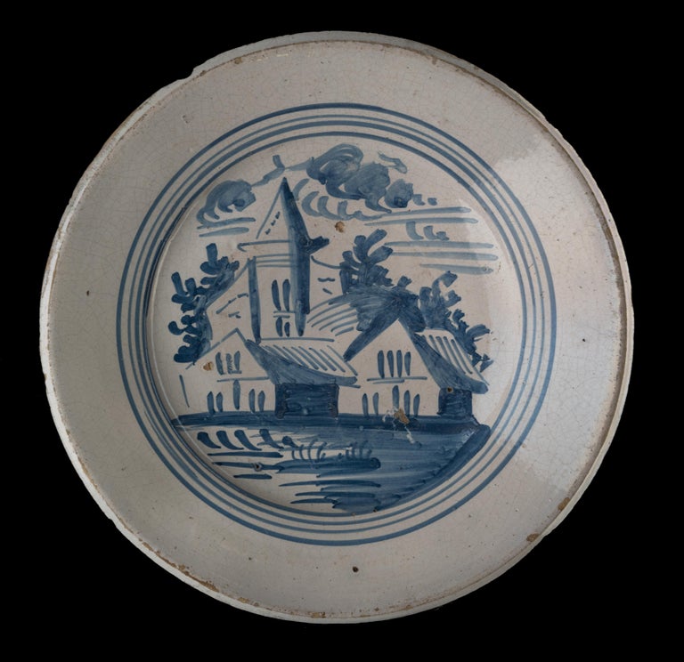 Blue and white landscape dish. Makkum, 1775-1800 
Tichelaar pottery. painter: Douwe Klases Hofstra [attributed to] 

The dish has a wide and raised flange and is painted in blue with a simplified village view, framed within four circles. The