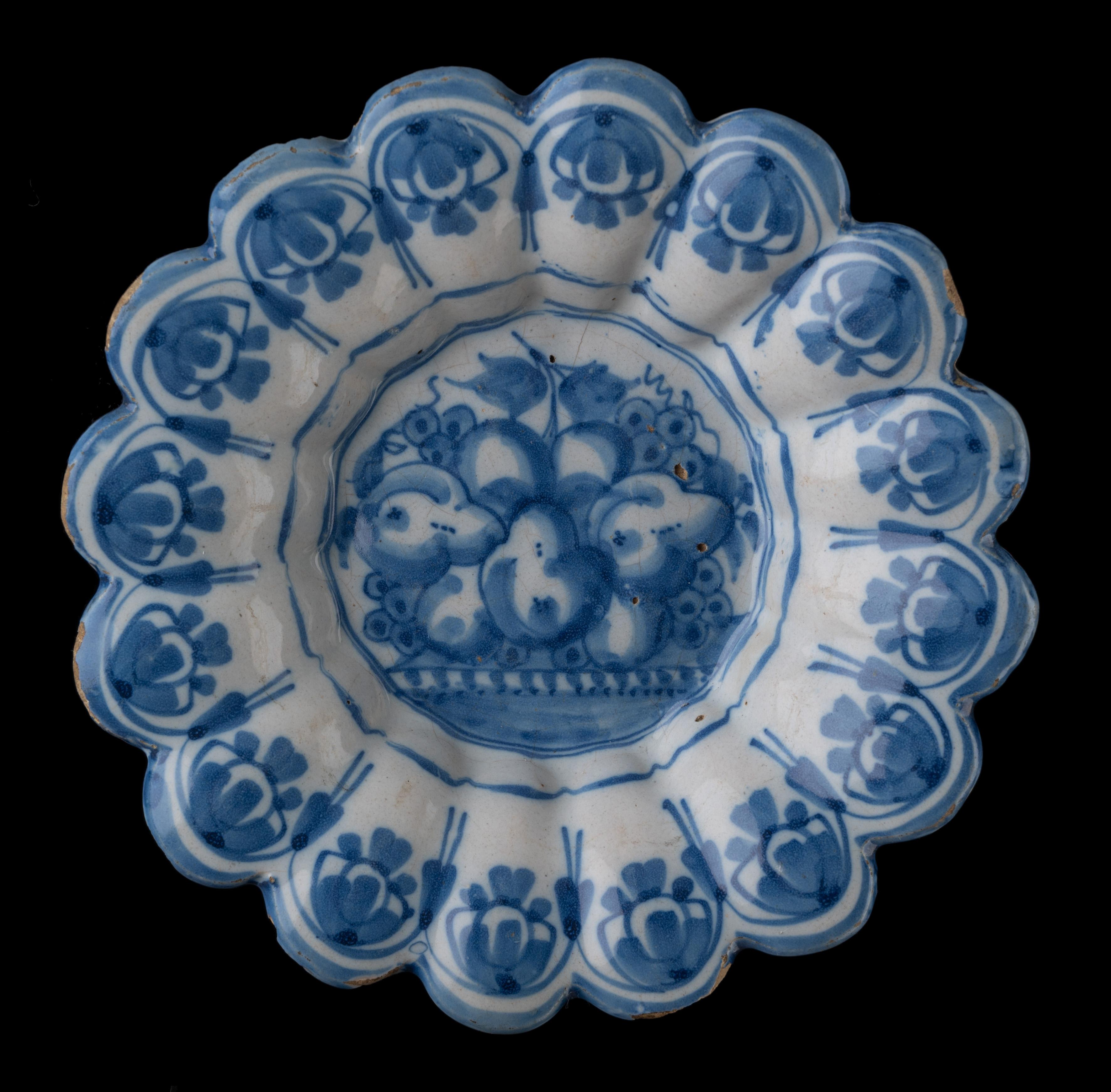 Blue and white lobed dish with fruit still life. Northern Netherlands, 1650-1680
Dimensions: Diameter 22,9 cm / 9.01 in.

The blue and white lobed dish is composed of sixteen small lobes and is painted in the centre with a still life of three