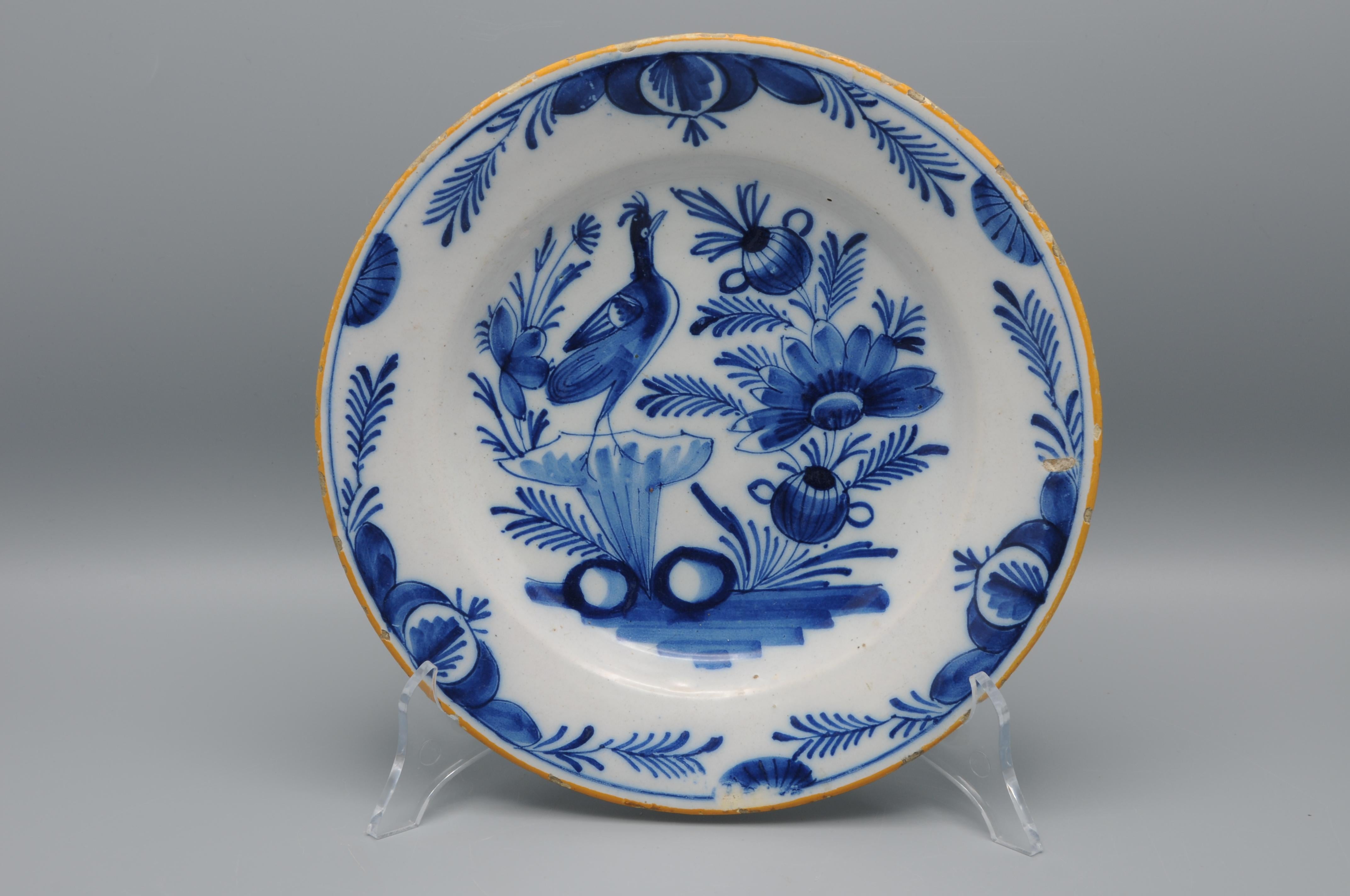  Assiette en faïence du début du 19e siècle à décor bleu d'un oiseau dans un paysage floral. Les jantes sont jaunes. 

Bon état ; seule une légère usure habituelle au niveau du bord. Un petit éclat dans le glaçage
