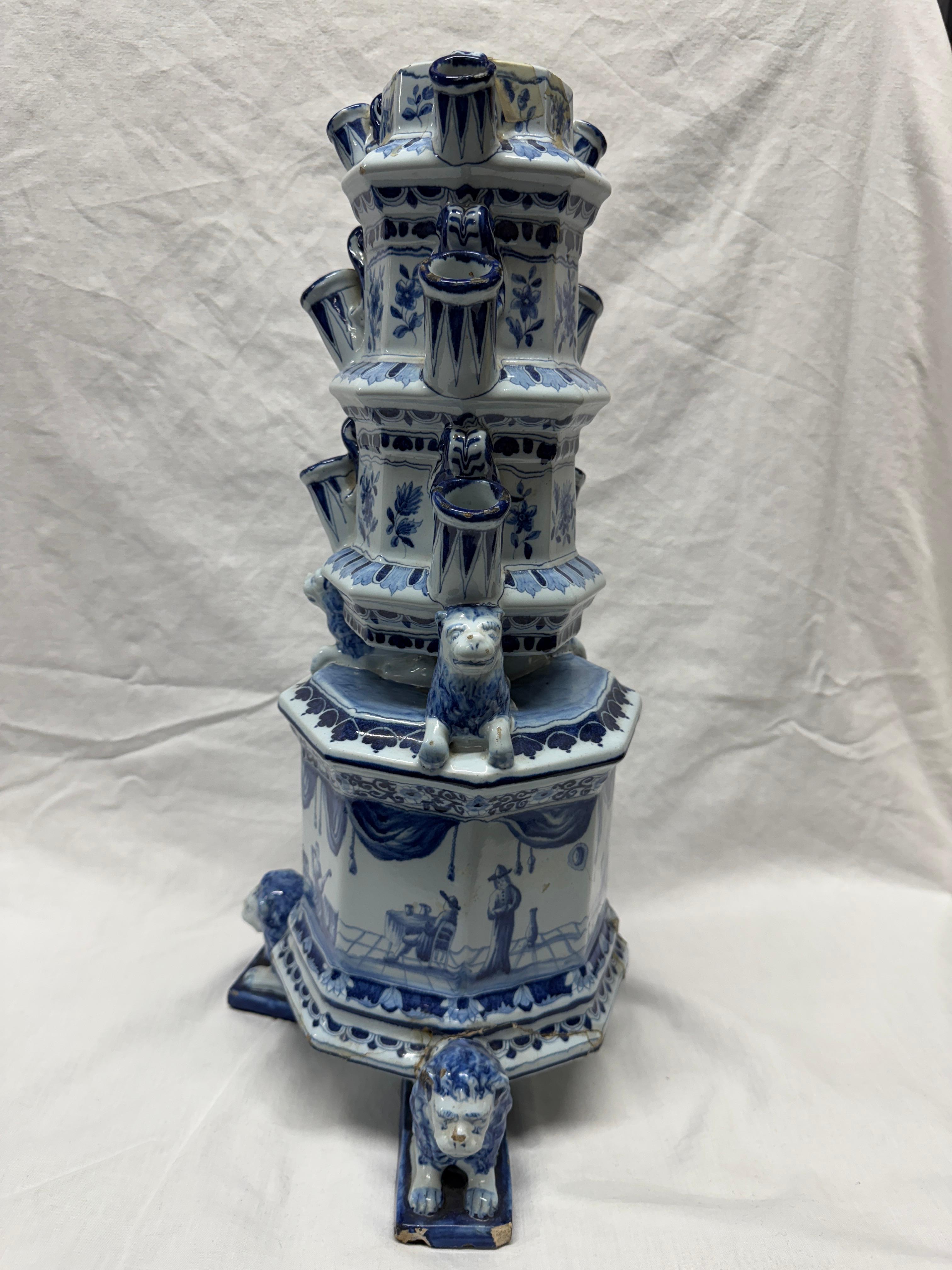 Vase à tulipe ou pyramide de fleurs de Delft, 19ème siècle, la base octogonale reposant sur trois lions couchés et peinte en bleu avec une scène continue de personnages dans un intérieur, surmontée de trois autres niveaux avec quatre ouvertures