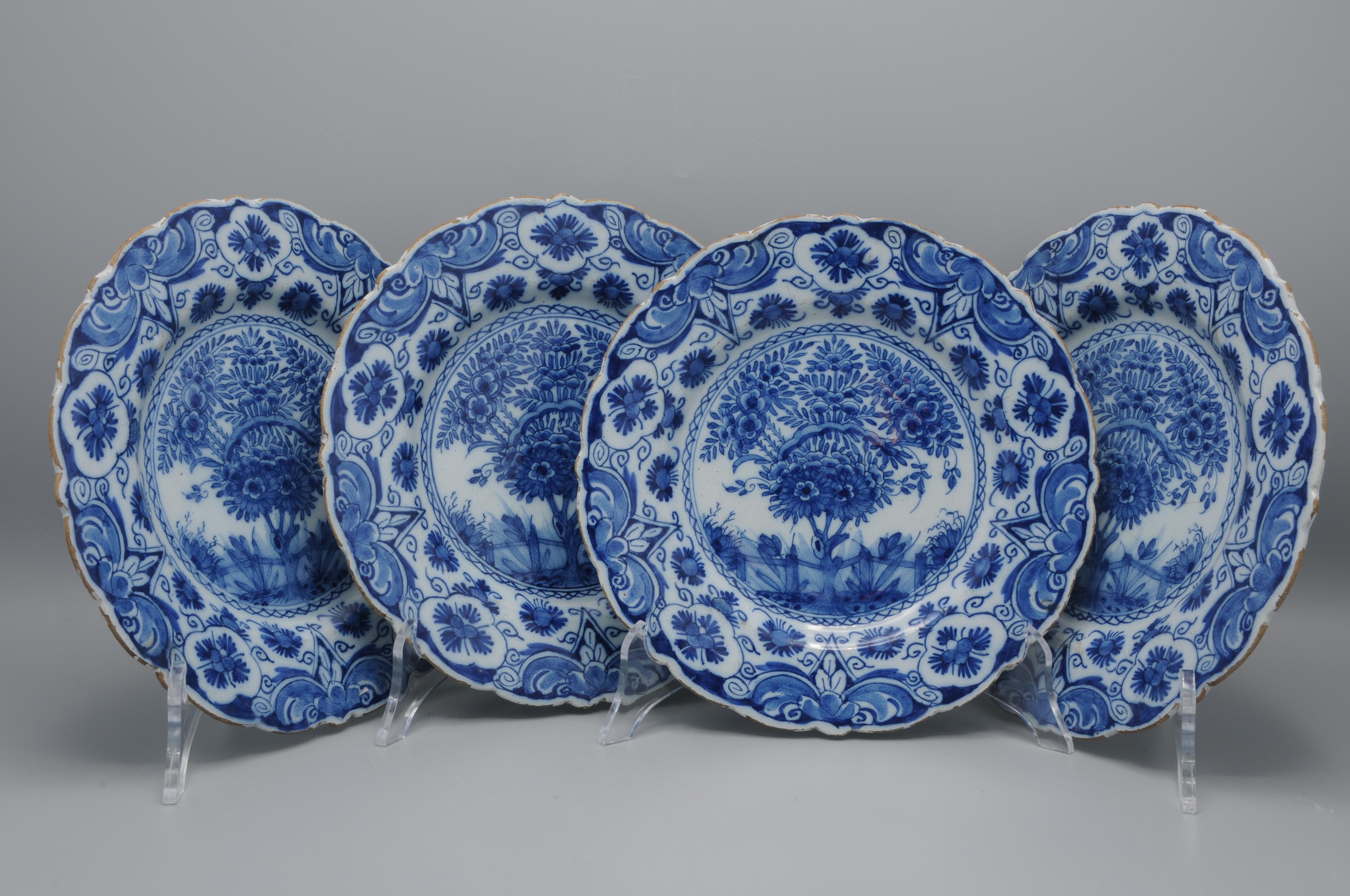 Cet ensemble comprend quatre assiettes Delft du milieu du XVIIIe siècle, chacune avec un bord festonné et un décor en bleu de cobalt. Le champ central montre un arbre unique s'élevant sur un rocher stylisé, encadré par une étroite bordure de