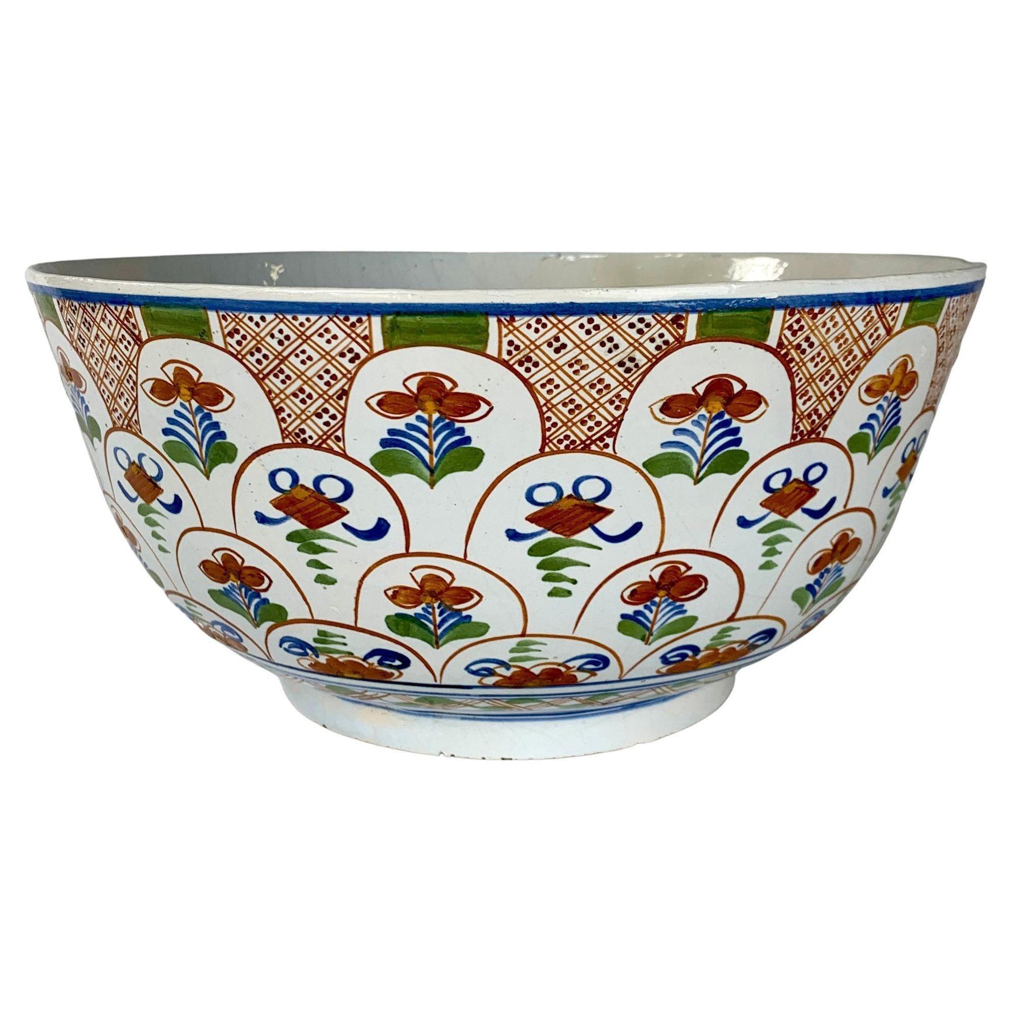 This group of a large Delft punch bowl with four corresponding Delft chargers was made in the Netherlands in the 18th century, circa 1780.
Each piece is hand painted with iron red tulips, some budding, some in bloom, and some as bulbs. The tulips