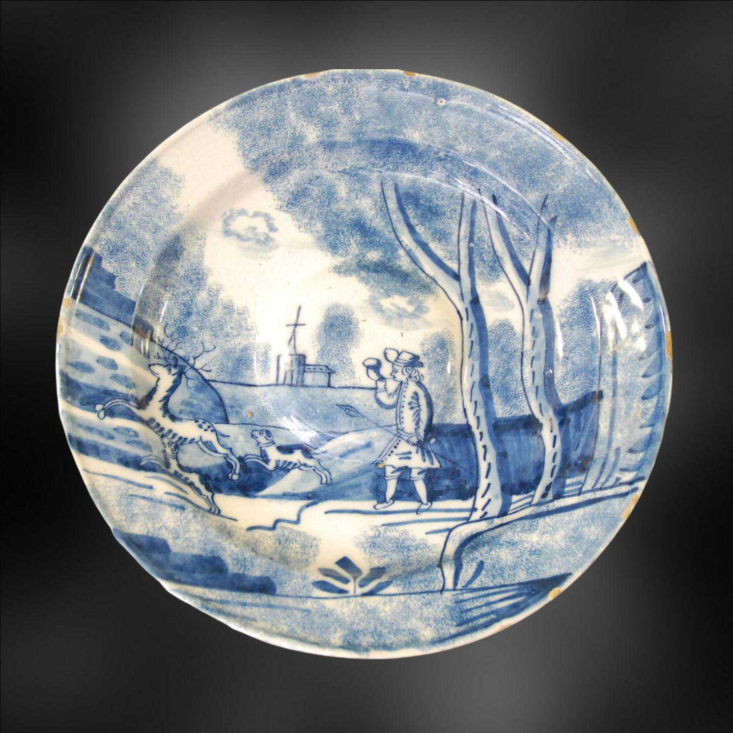 Tin glazed earthenware (Delftware) dish, in an unusual shape; elaborately and skillfully painted with a man coursing a stag. Probably London; perhaps Bristol. Probably the salver for a large ewer.

English Delftware is considered to be one of the