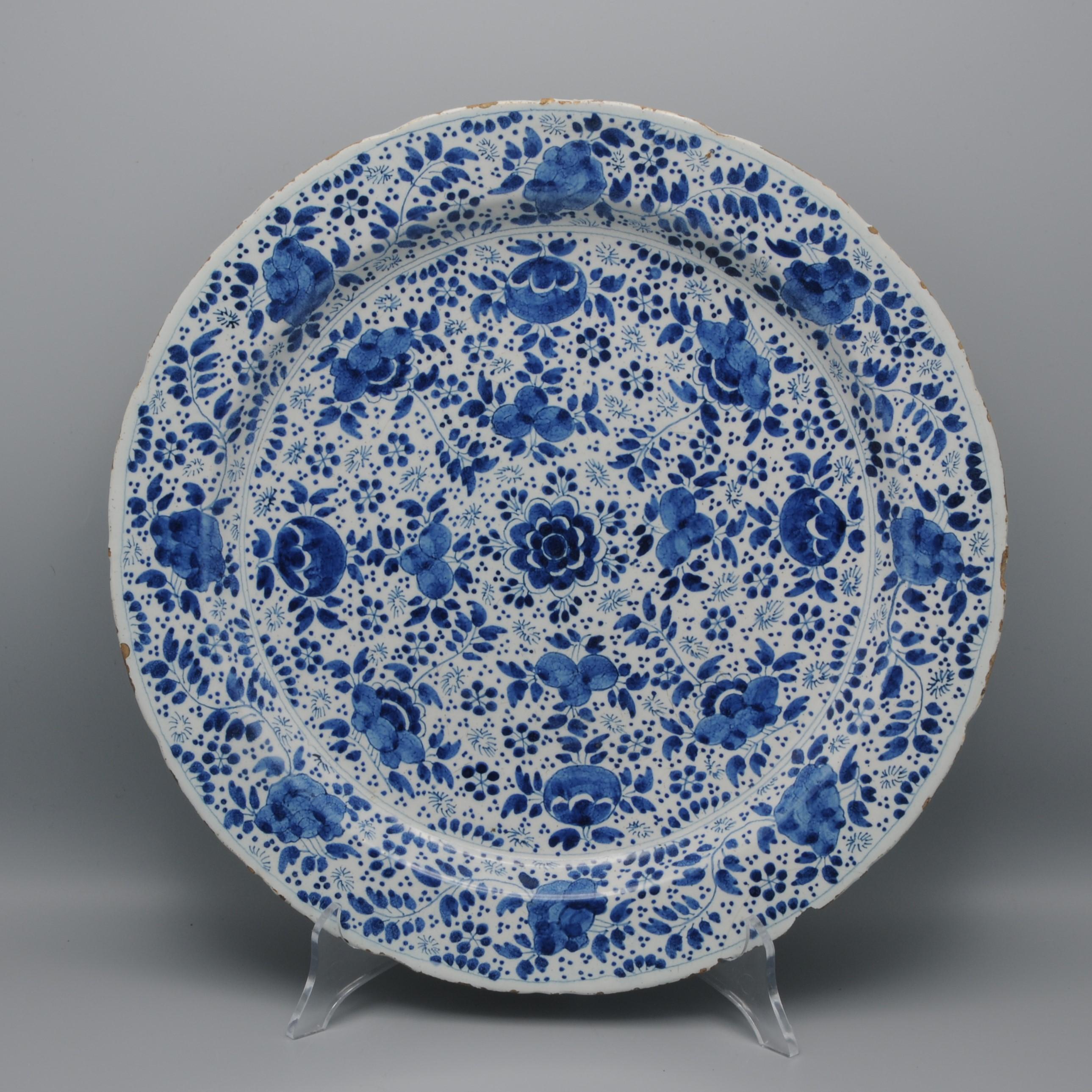 Assiette en faïence bleue du début du 18e siècle avec un magnifique décor de fleurs, de feuillages et de brindilles 