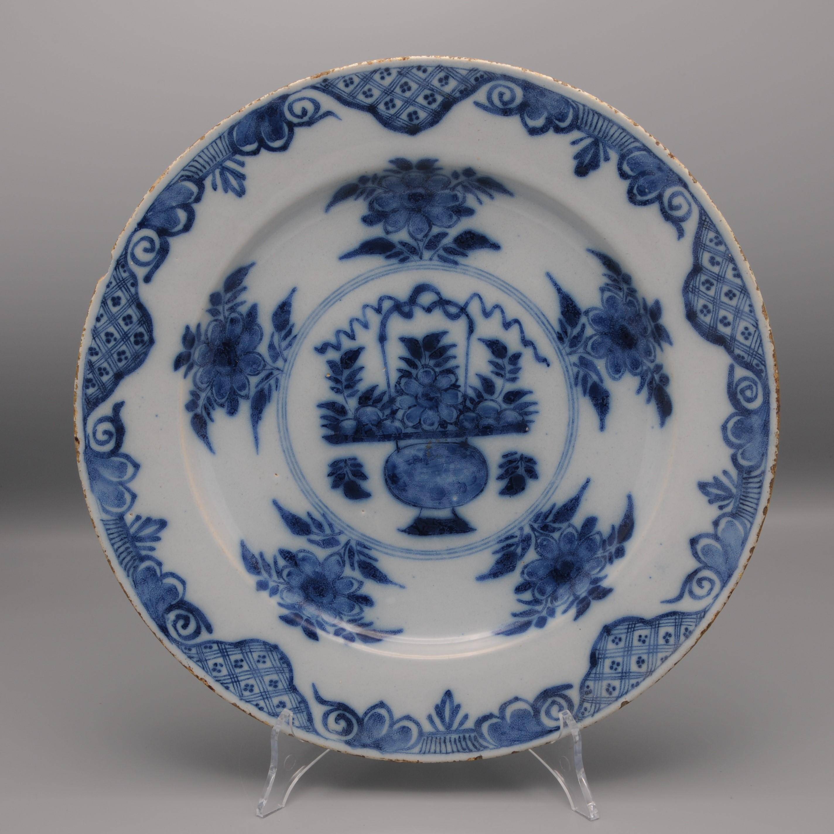 Mid 18th century Blue Delftware platter with Chinoiserie decoration of a flowering basket amidst floral sprigs
Beautiful border decoration of rich foliage, flowers and scrollwork.
Unmarked
Good quality of painting
Good condition; only usual  wear