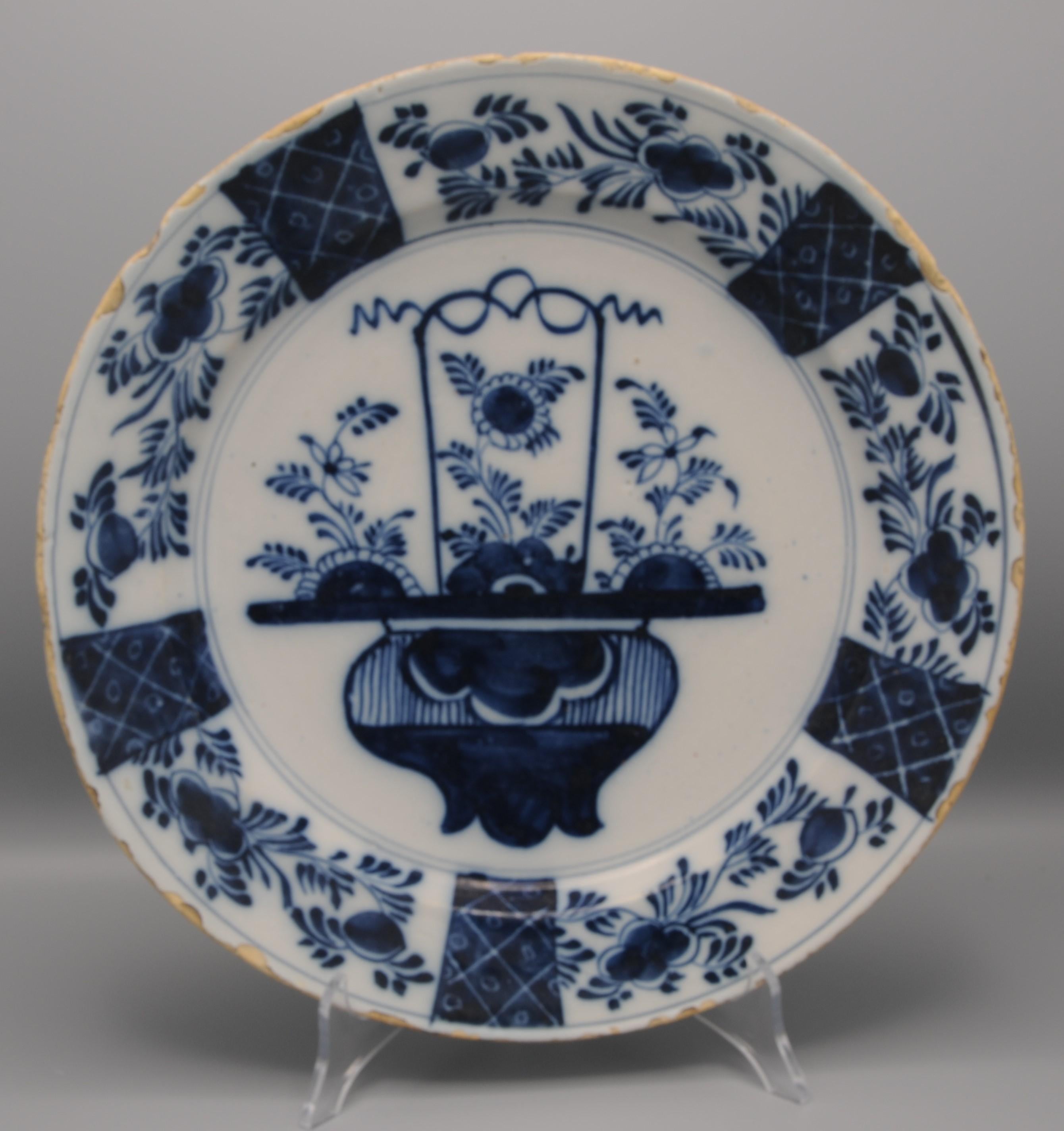 Mid 18th century Blue Delftware platter with Chinoiserie decoration of a flowering basket. 
Beautiful border decoration of alternating panels with foliage and tracery
Unmarked
Good quality of painting
Good condition; only usual wear and a little