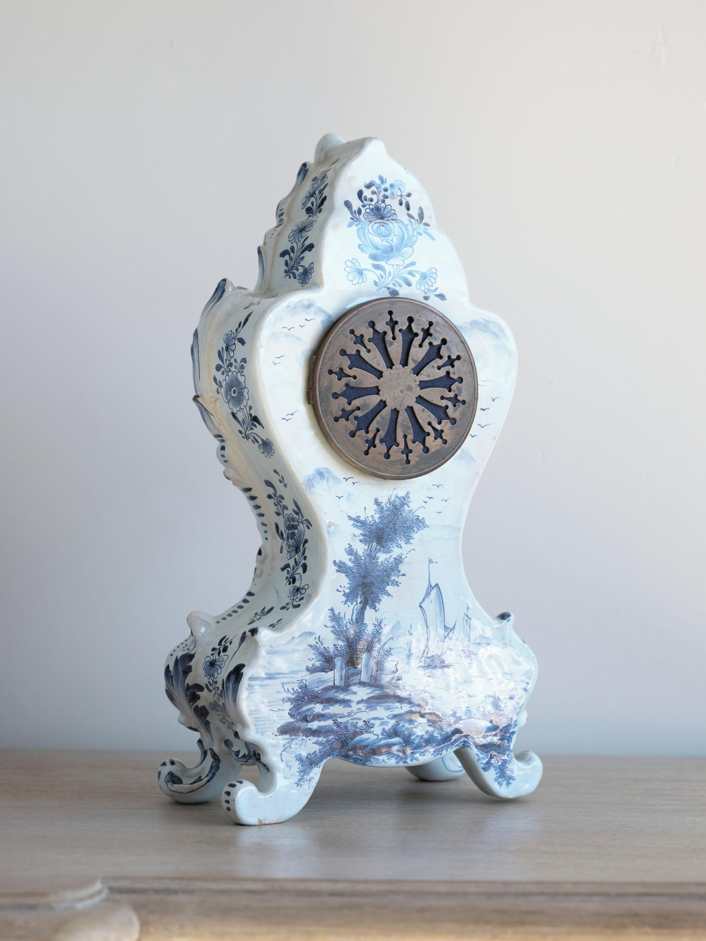 Keep time in your office or home with this charming blue and white 19th Century Delft Clock. Crafted in the Netherlands in the 1800s, this working porcelain piece stands on 4 legs and includes the original pendulum and hardware. Pendulum and winding