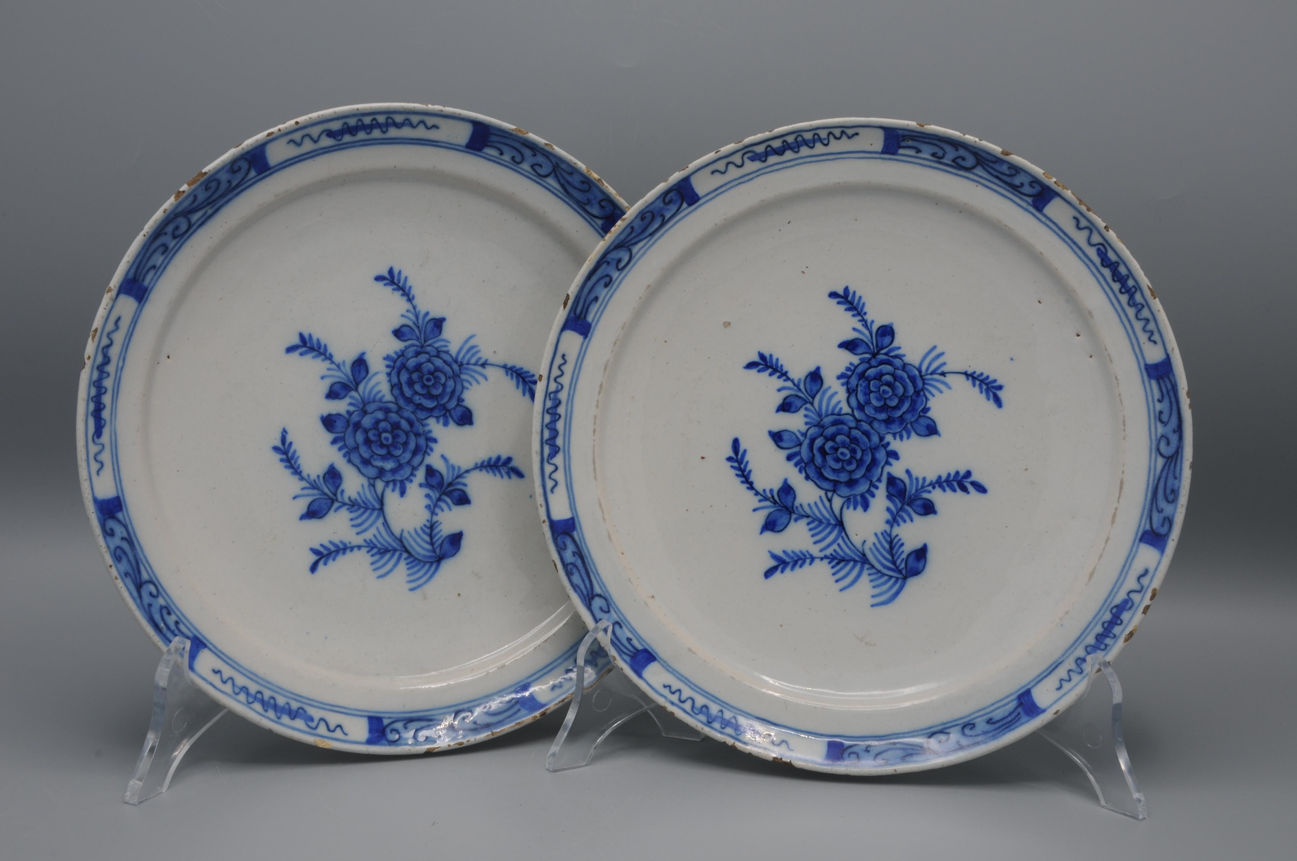 Paire d'assiettes en faïence de Delft, datant du XVIIIe siècle, peintes à la main en bleu de cobalt sur un fond blanc émaillé à l'étain. Chaque assiette est ornée d'une branche centrale florale avec deux roses ( ?) entourée de petites branches