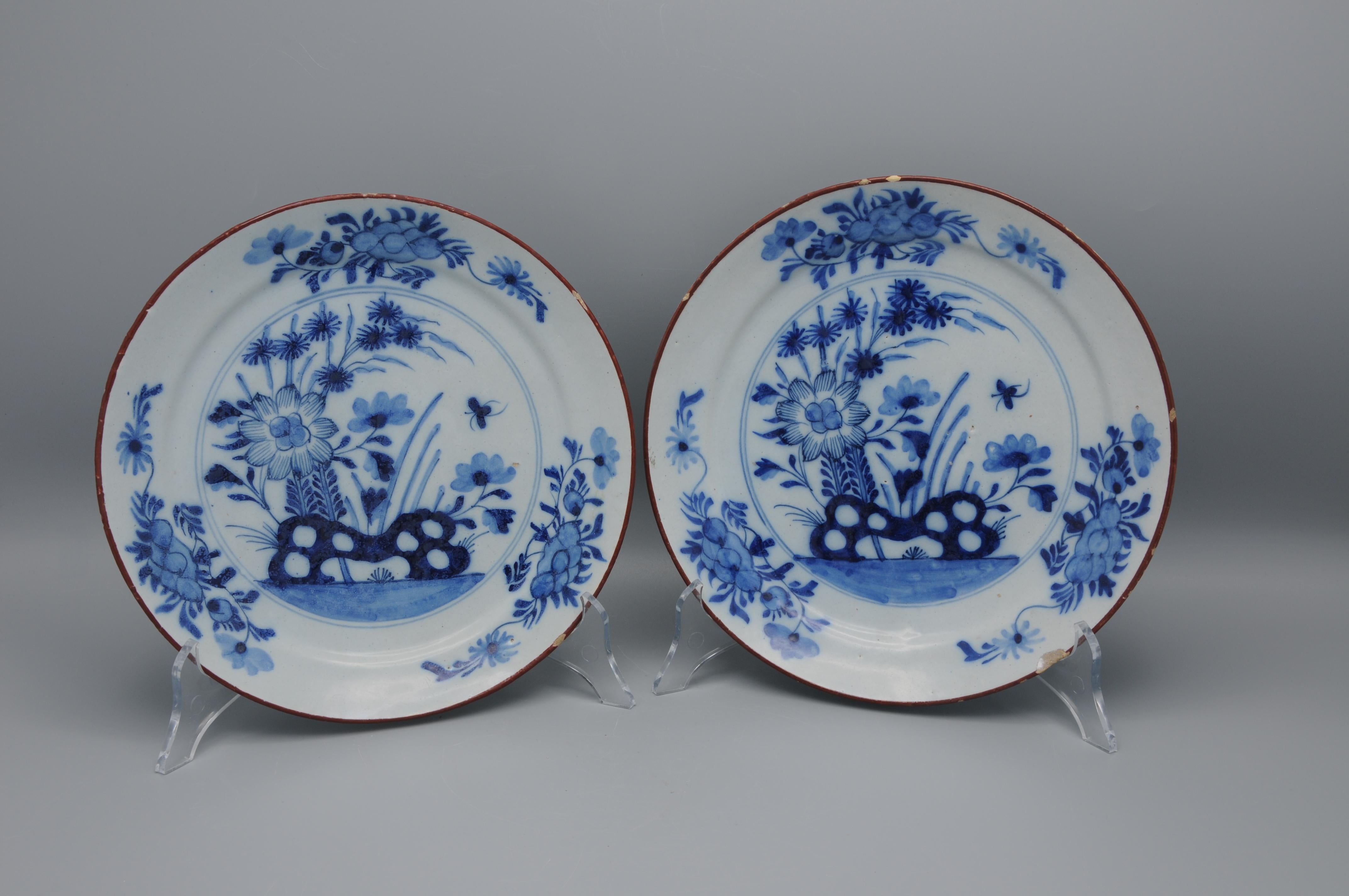 Good pair of 18th century Dutch Delft Blue chinoiserie dishes decorated with a oriental central flower arrangement behind a rock. The borders adorned with 3 foliage sprigs and brown rims. Very decorative plates. 

unmarked
Some chipping and wear to