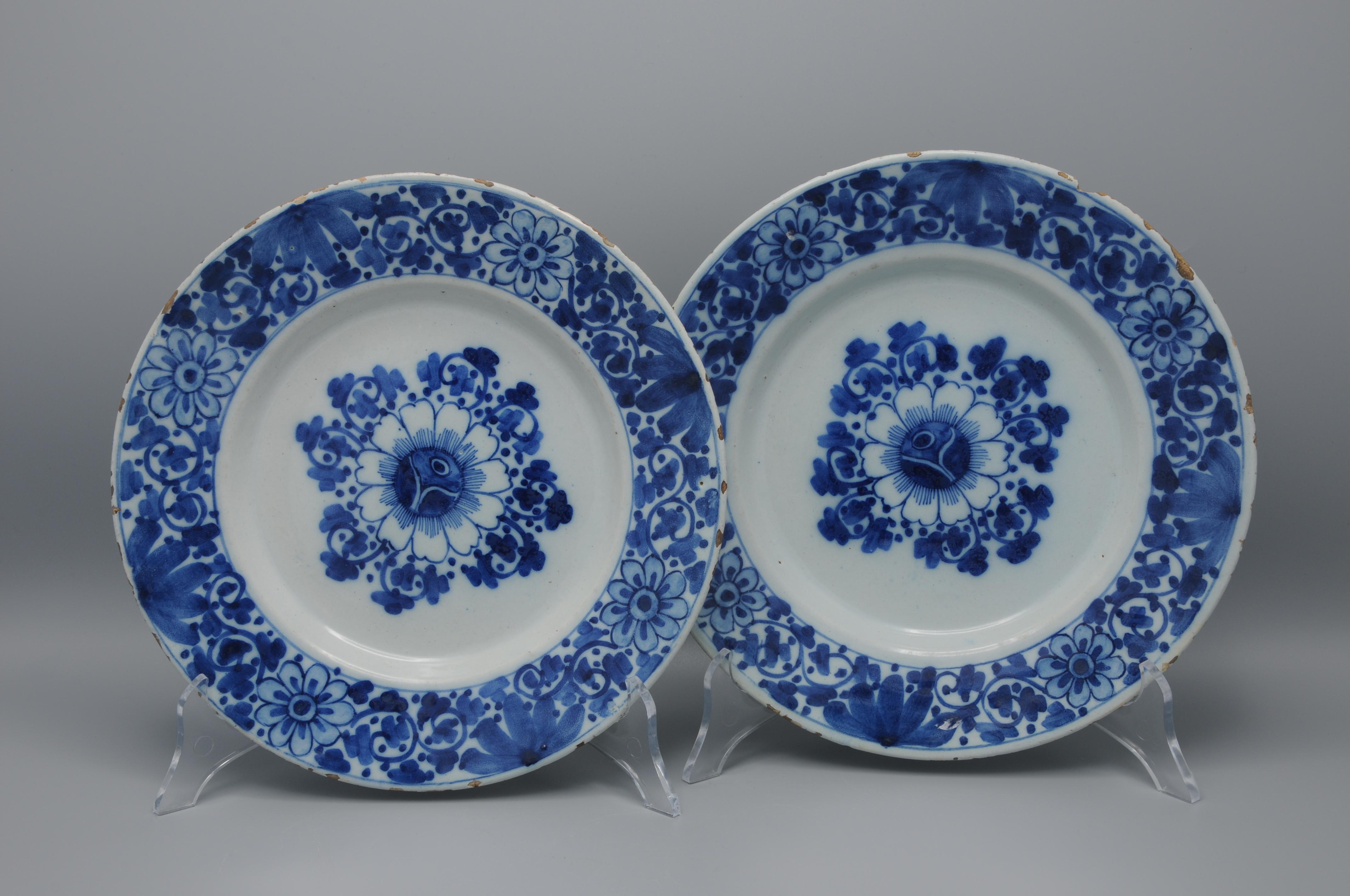 Buen par de platos holandeses del siglo XVIII, de color azul de Delft, decorados con una disposición geométrica de una flor central, adornada con volutas de follaje. Los bordes están ricamente adornados con follaje y flores similares. Láminas muy