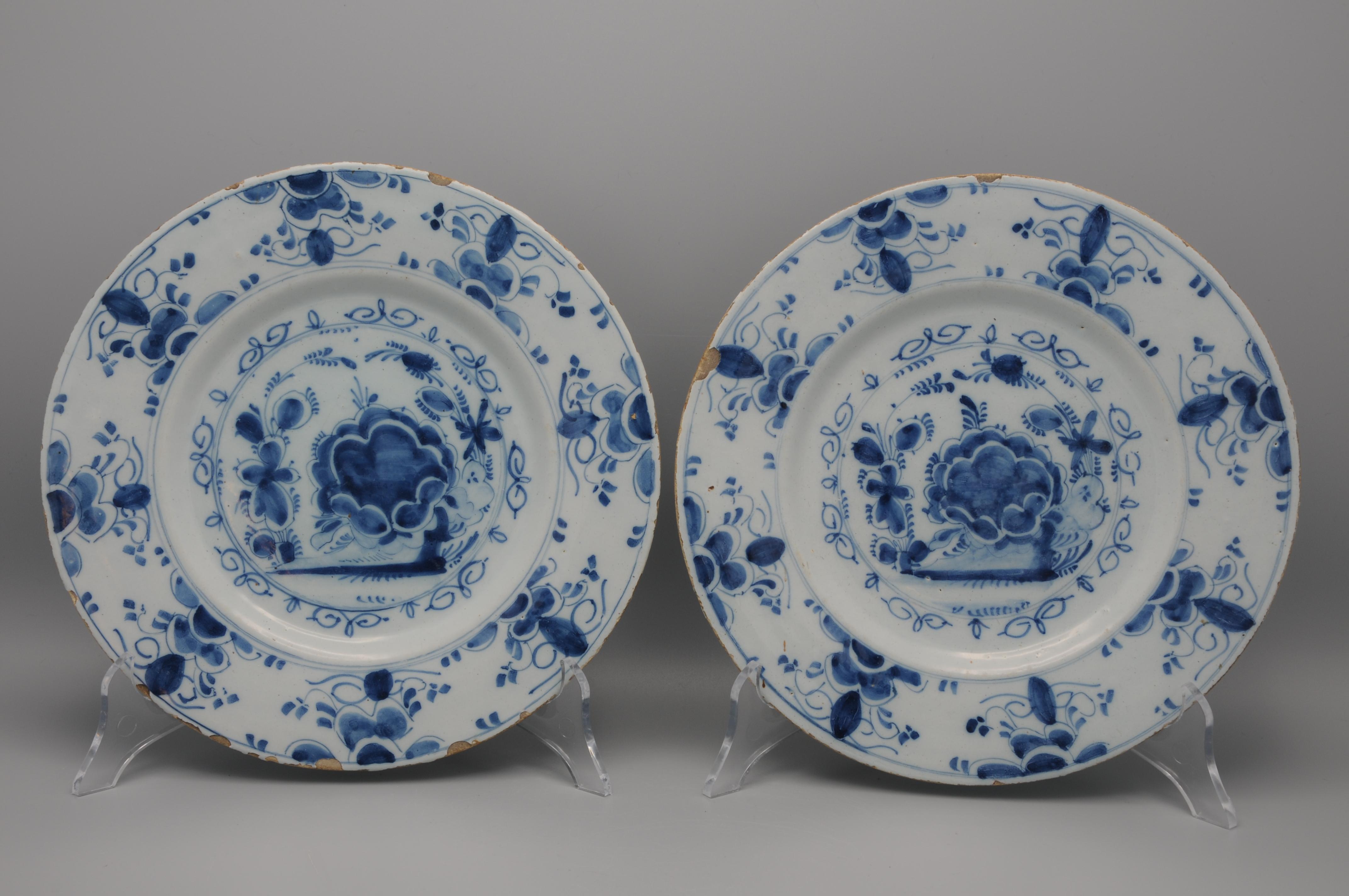 Buen par de platos holandeses del siglo XVIII, de color azul de Delft, decorados con una estilizada disposición de una flor central, adornada con volutas de follaje. Los bordes están ricamente adornados con follaje y flores similares. Láminas muy