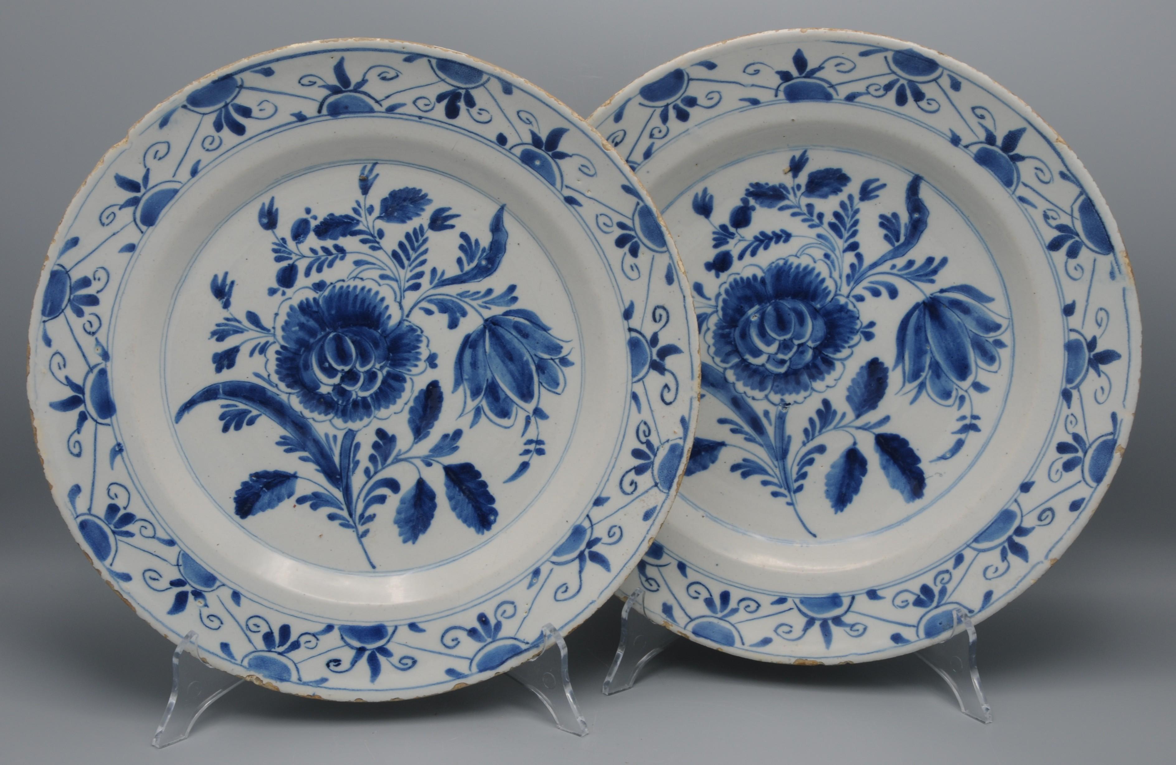Bonne paire de plats hollandais en bleu Delft du XVIIIe siècle, décorés d'une belle composition florale centrale composée d'une tulipe, d'une pivoine et de feuillage. Les bordures sont richement ornées de rinceaux de feuillage. Plaques très