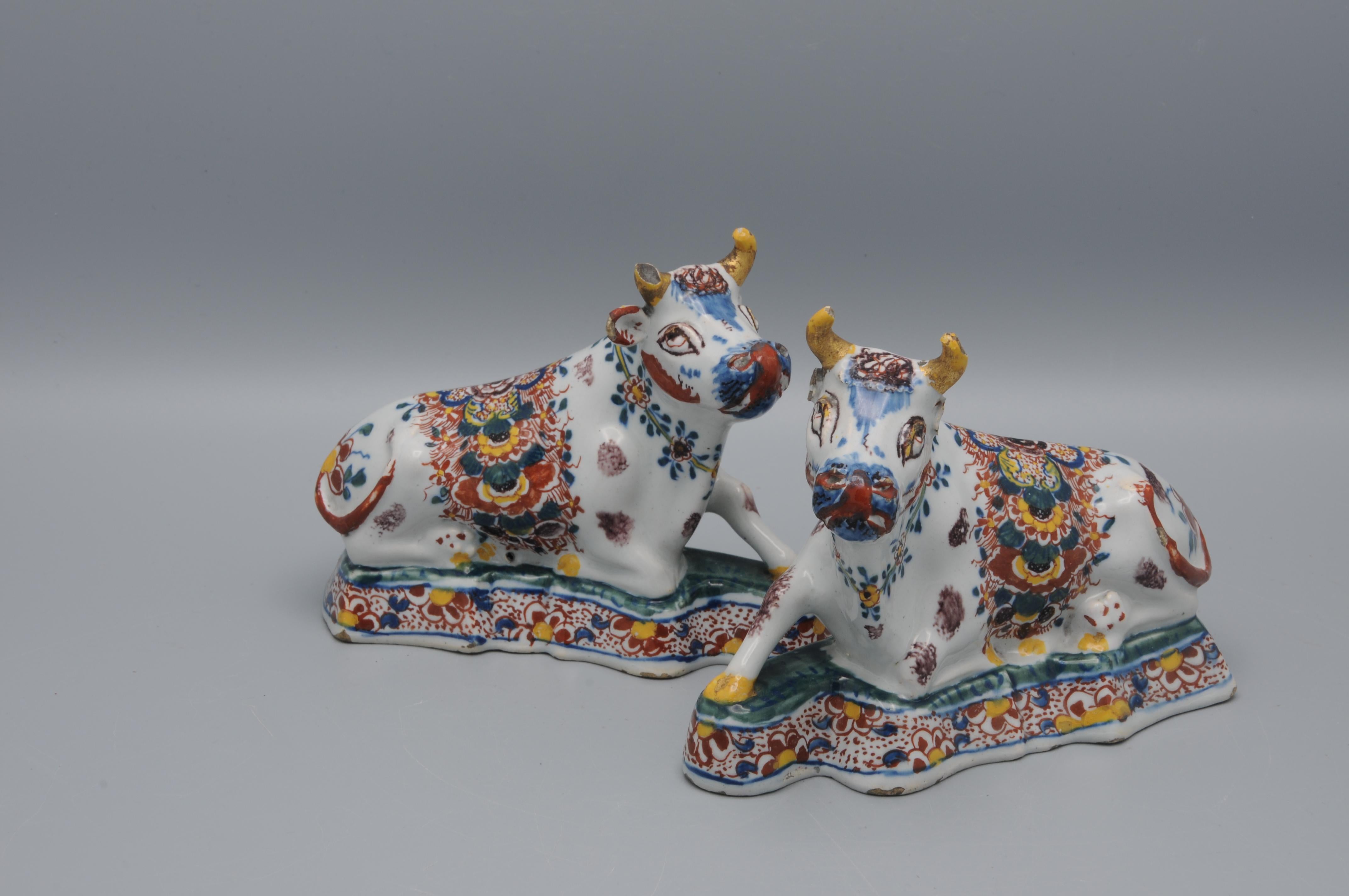 This pair of Delftware recumbent cow figurines, dating to the late 18th century, exemplifies the Dutch tradition of molded earthenware crafted in the city of Delft. They are cast 'affronté' facing each other. The decoration in iron-red, yellow,