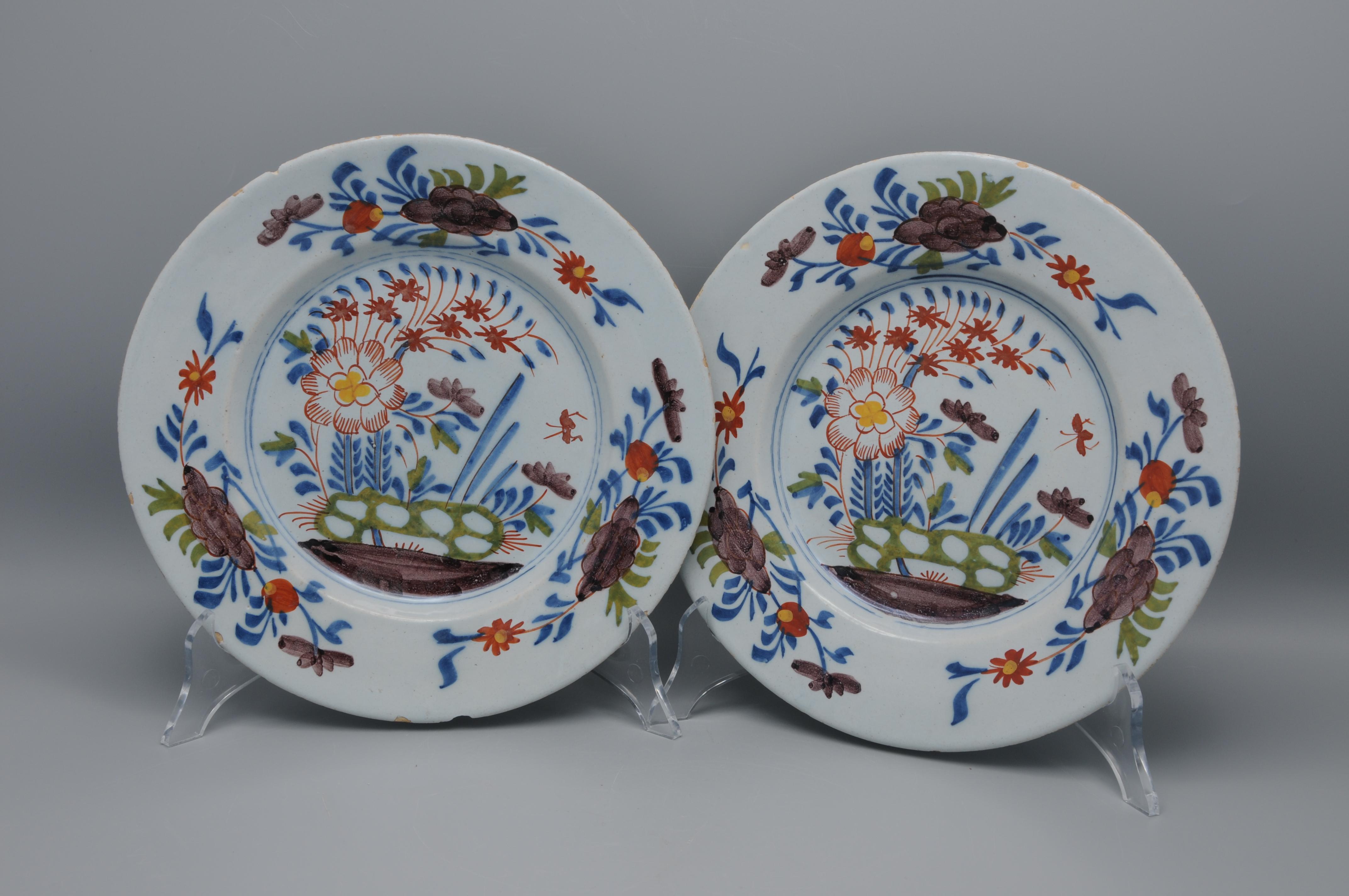 Good pair of 18th century Dutch Delft polychrome chinoiserie dishes decorated with a oriental central flower arrangement behind a rock. The borders adorned with 3 foliage sprigs. Very decorative plates. 

unmarked
Some chipping and wear to the rims.