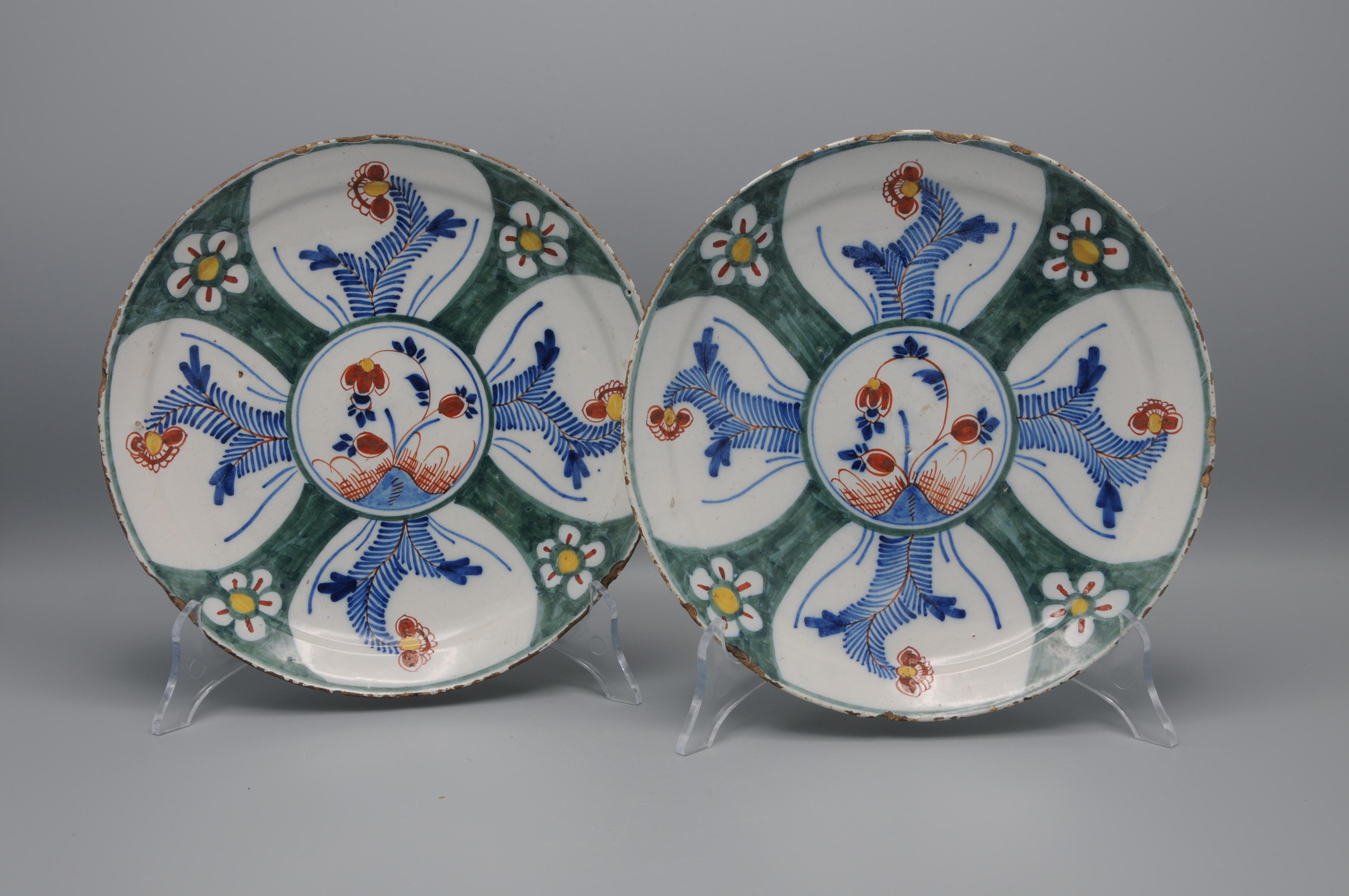Excellent pair of 18th century Dutch Delft polychrome plates decorated with a geometrical arrangement of a central flower, adorned with foliage scrolls. The borders richly adorned with similar foliage and flowers on a green background. Very