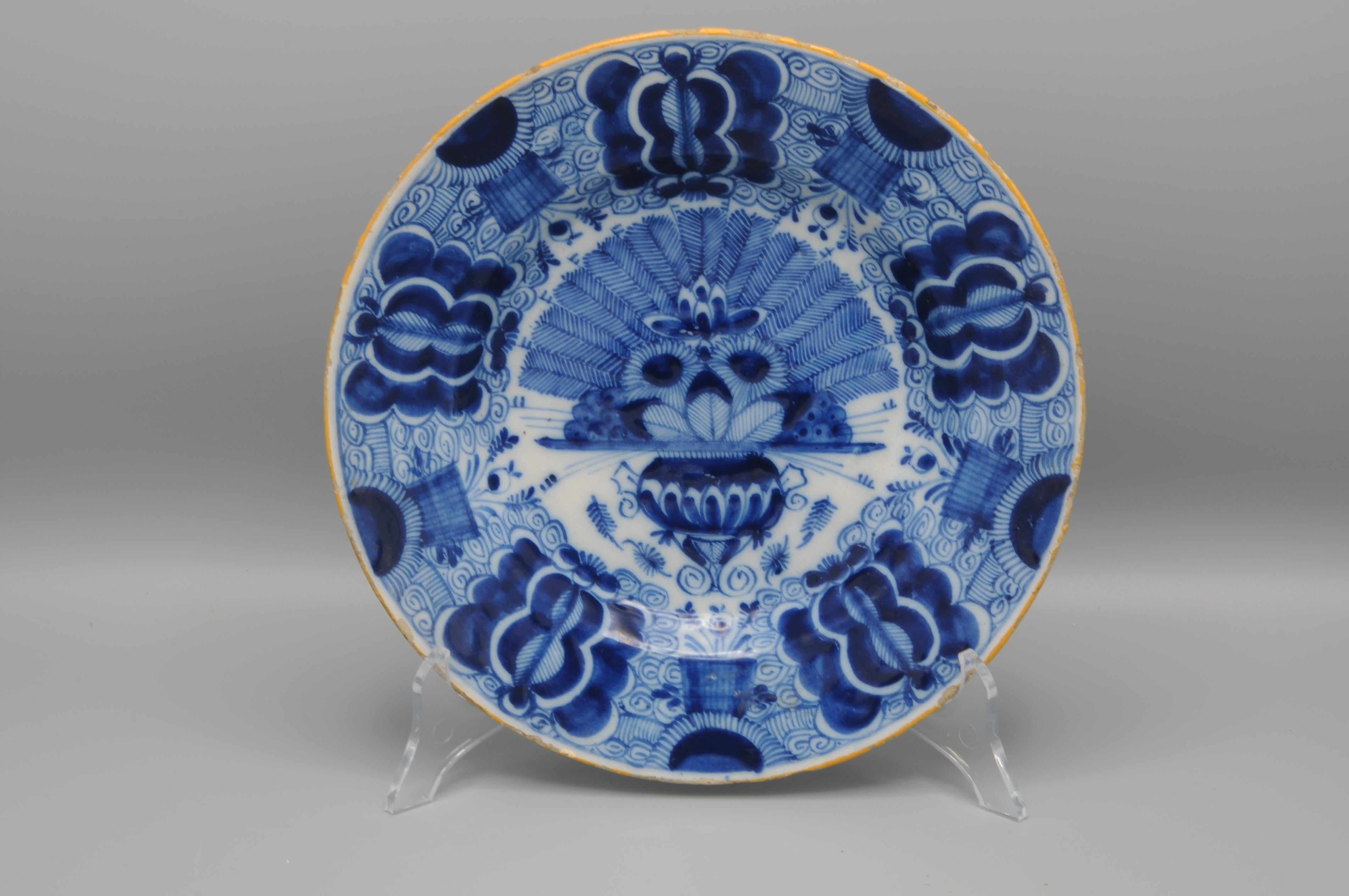 Dutch Delft blue and white 'Peacock' plate, 18th century, with ochre rim, the center decorated in cobalt with a vase containing an arrangement of peacock feathers and flowers. The rim decorated with stylized flower heads against a scrolling