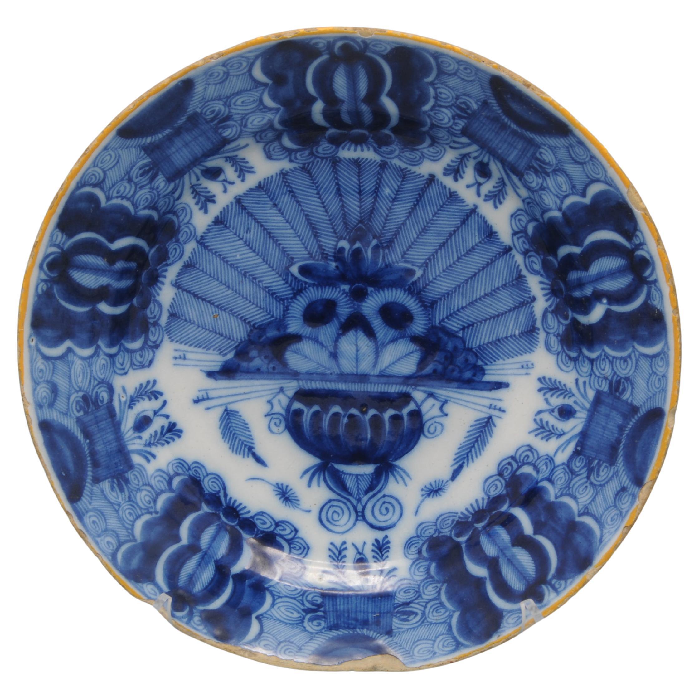 Dutch Delft blue and white 'Peacock' plate, 18th century, with ochre rim, the center decorated in cobalt with a vase containing an arrangement of peacock feathers and flowers. The rim decorated with stylized flower heads against a scrolling