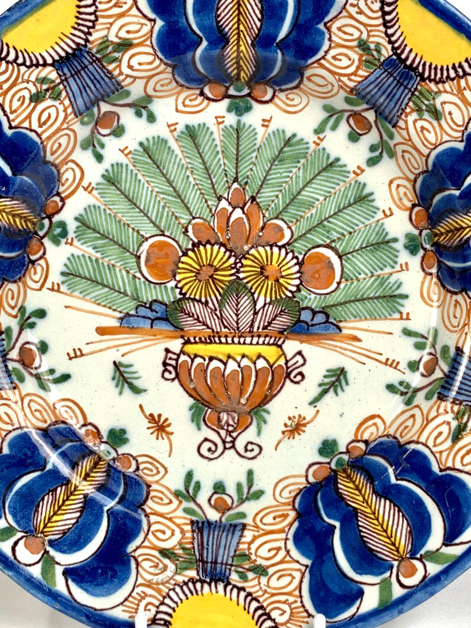 This Dutch Delft plate is a wow visually!
Made in the factory of De Porceleyn Lampetkan (The Porcelain Ewer) in the city of Delft circa 1760, it was hand-painted in bold polychrome colors of yellow, blue, iron red, green, and purple.
The center
