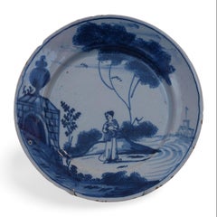 Delft plate with a woman passing a monument. England C1745.
