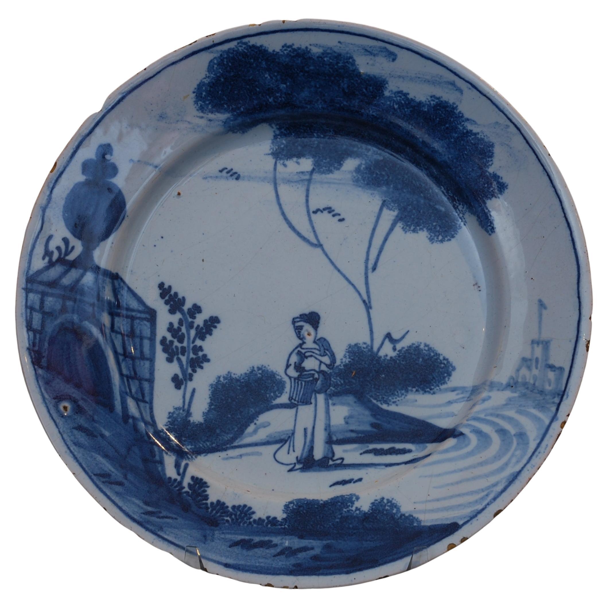 Delft plate with a woman passing a monument. England C1745. For Sale