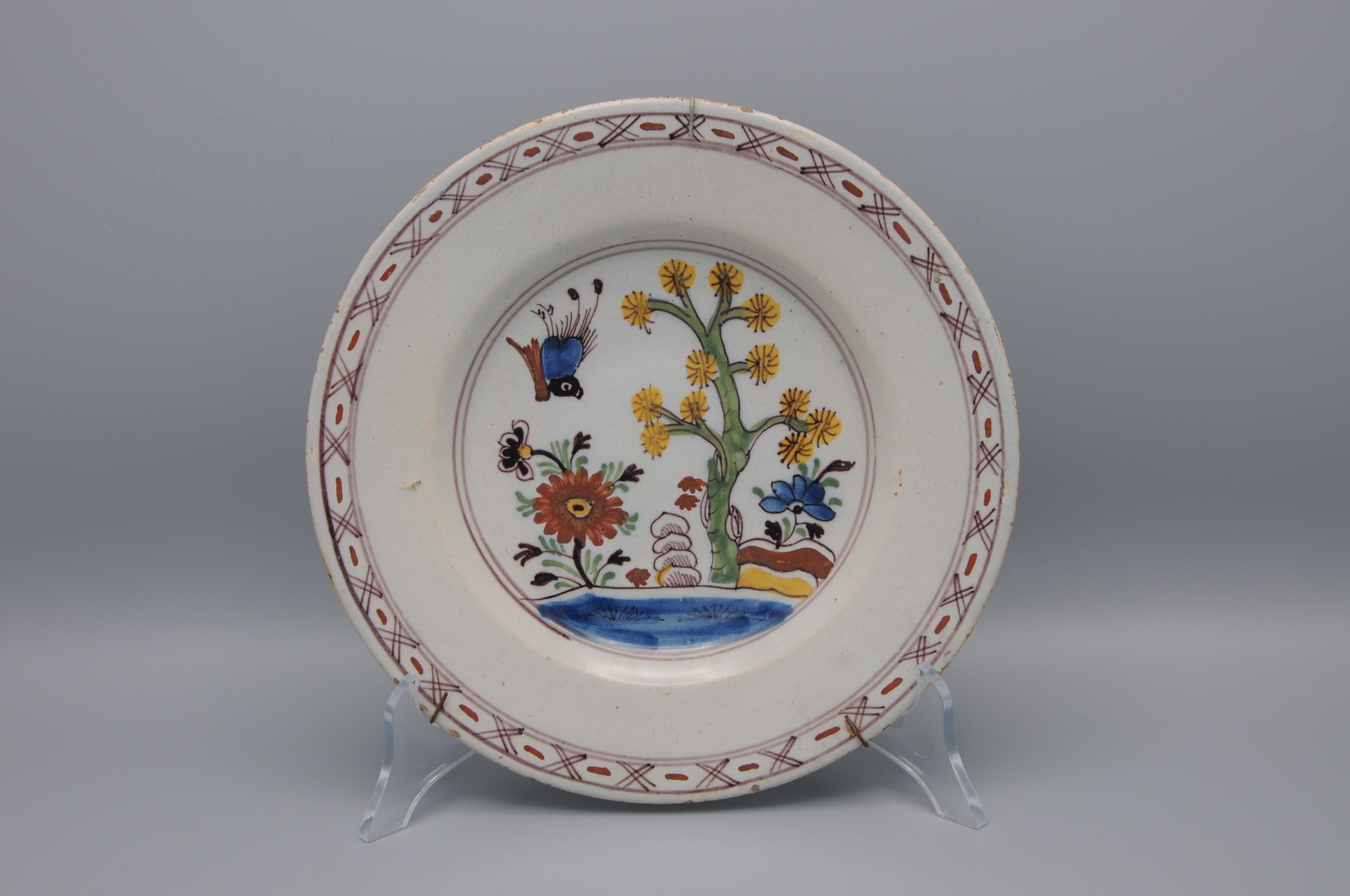 Assiette en faïence bleue du milieu du XVIIIe siècle avec un oiseau entrant dans un décor chinois de fleurs, d'un arbre en fleurs et de pierres au milieu d'arbustes. Style Qianlong. 

Non marqué

Bon état ; quelques ébréchures et usures sur