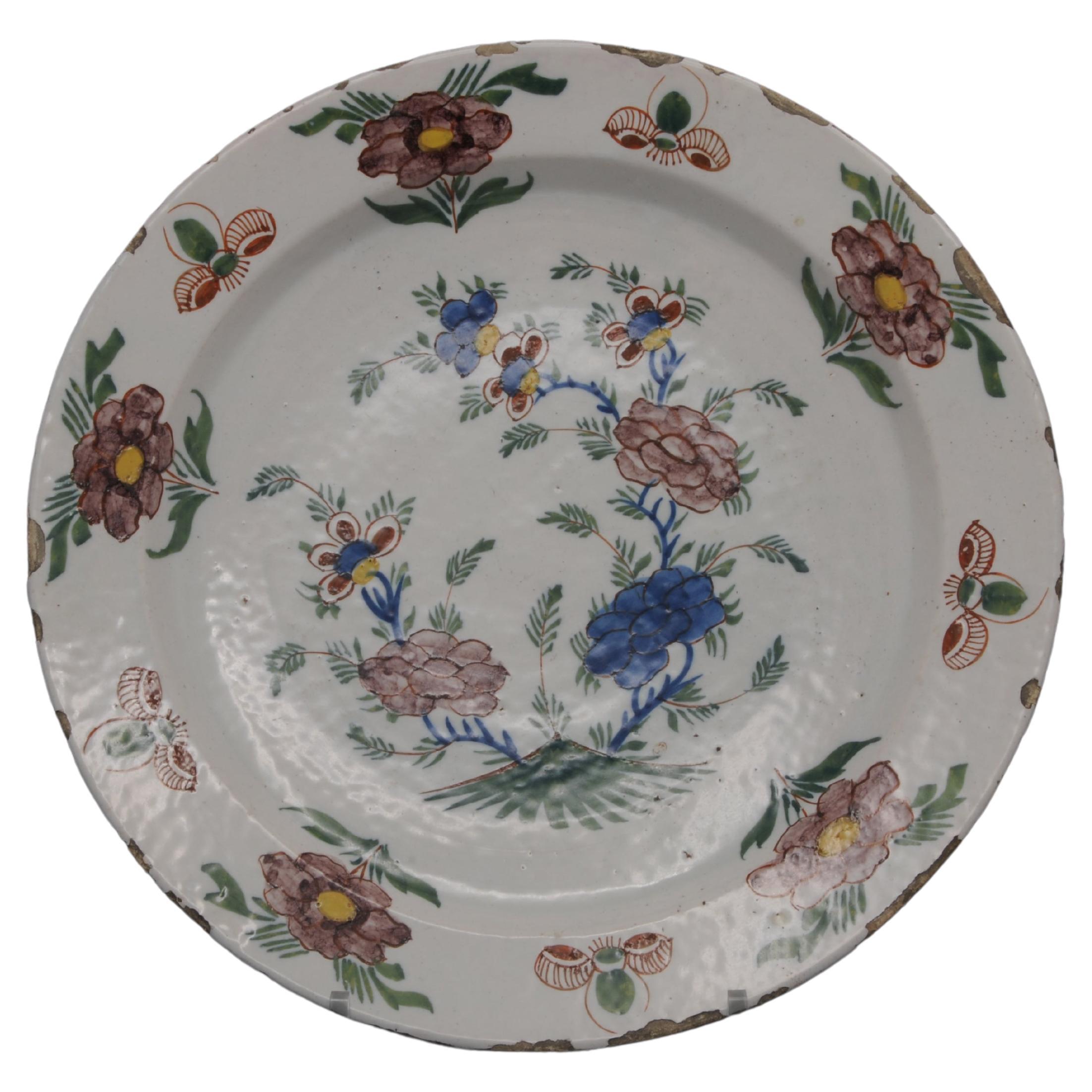 Polychrome Delftware plate with chinoiserie decoration of blossoming branches and flowers. The rim with alternating flowers and insects. Attractive colorscheme with soft manganese / purple. 
Unmarked

Good condition; usual chipping and wear to the