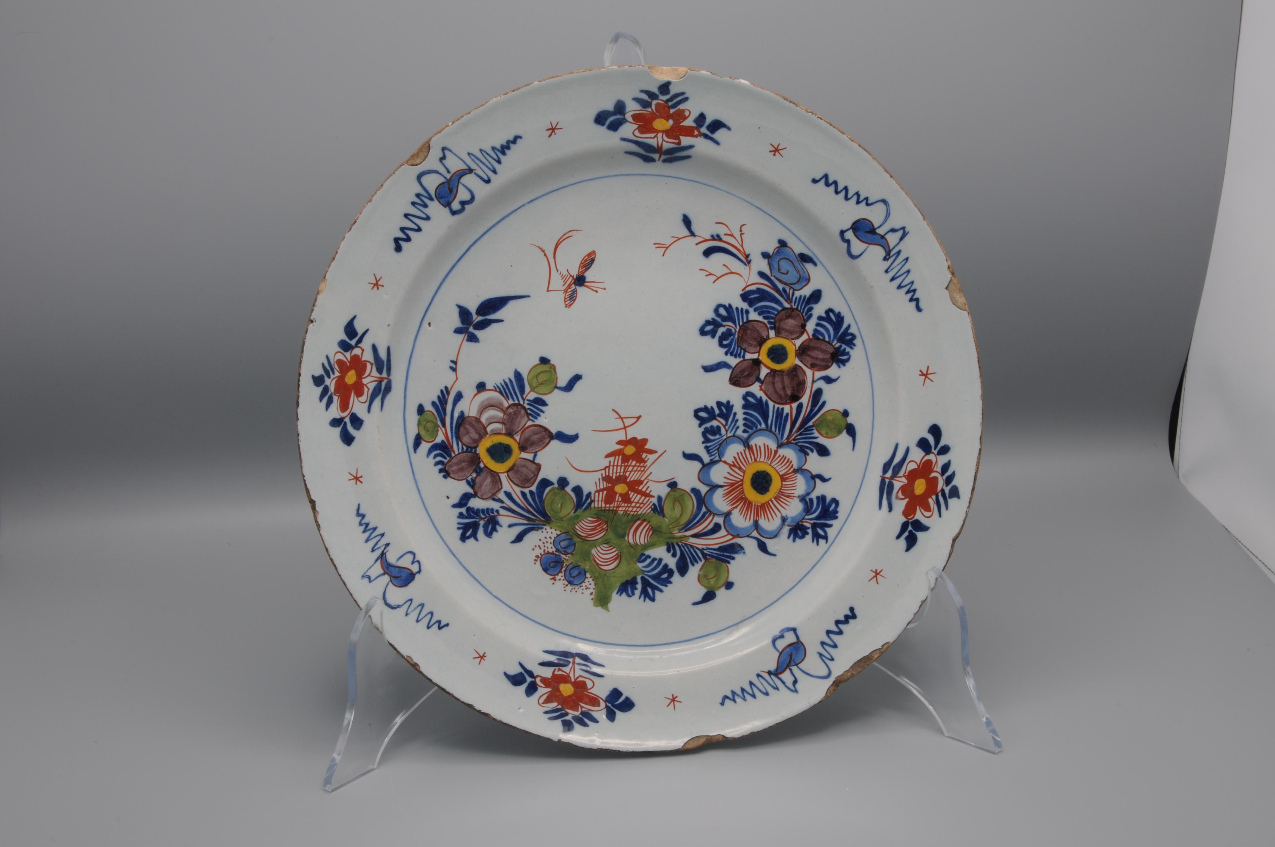 Polychrome Delftware plate with chinoiserie decoration of blossoming branches and flowers and insects. Bright vibrant colors. 
Unmarked

Good condition; usual chipping and wear to the rim.