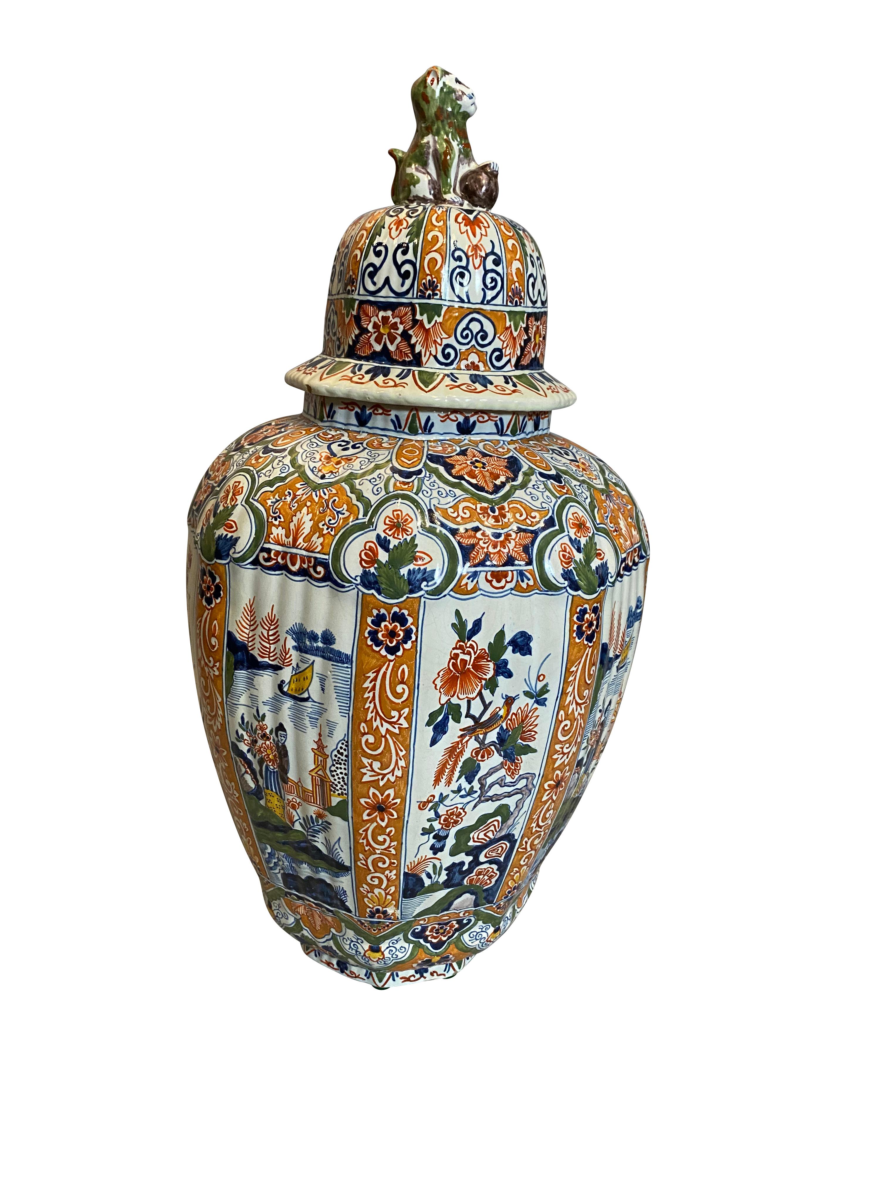 With lion form finial on the domed ribbed cover, baluster form vase with polychrome decoration.