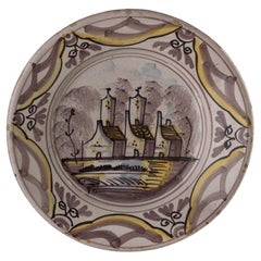 Plat polychrome de Delft avec une vue de village aux Pays-Bas, 1675-1725