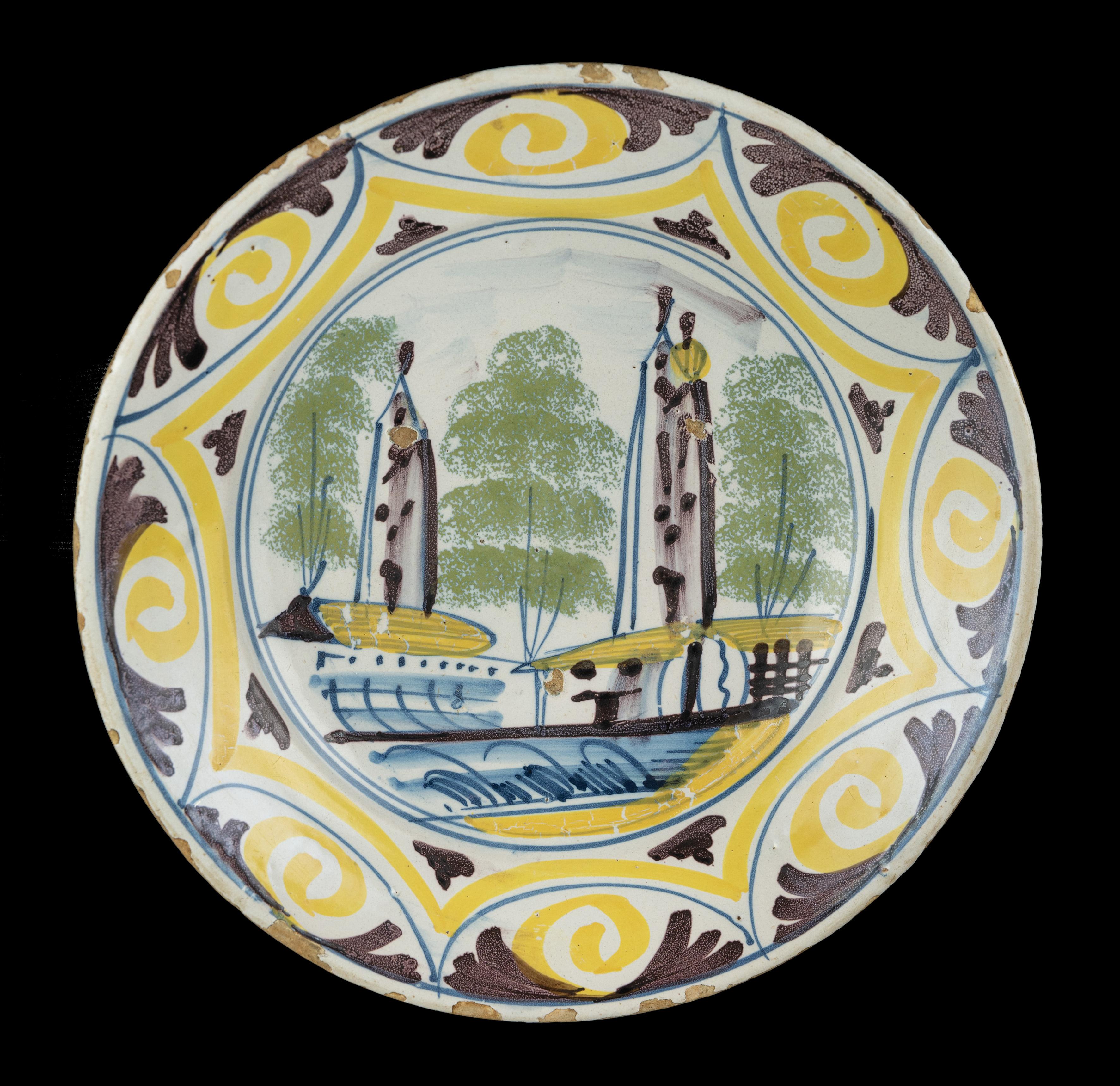 Polychrome dish with a village view. The Netherlands, 1700-1750 

The dish has a spreading, slightly raised rim and is painted in blue, purple, yellow and green with a simplified village view of two towers with houses and trees in a double circle.