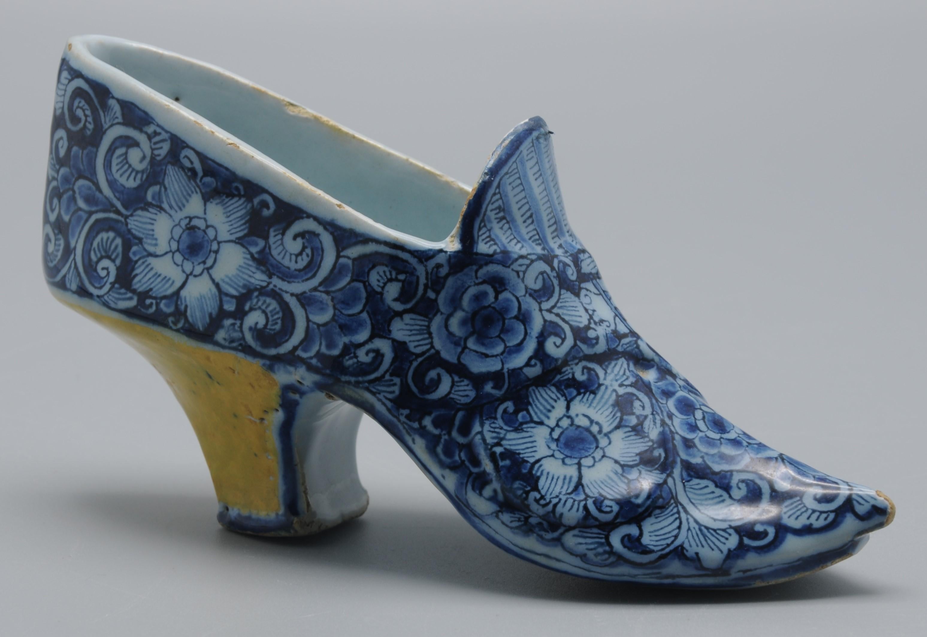 Modèle de pantoufle ou de chaussure en bleu et jaune de Delft. Motif de fleurs, talon lavé en jaune. 

Restauration sur la tranche supérieure. Principalement visible de l'intérieur.  

14 cm de long, 7 cm de haut.  
