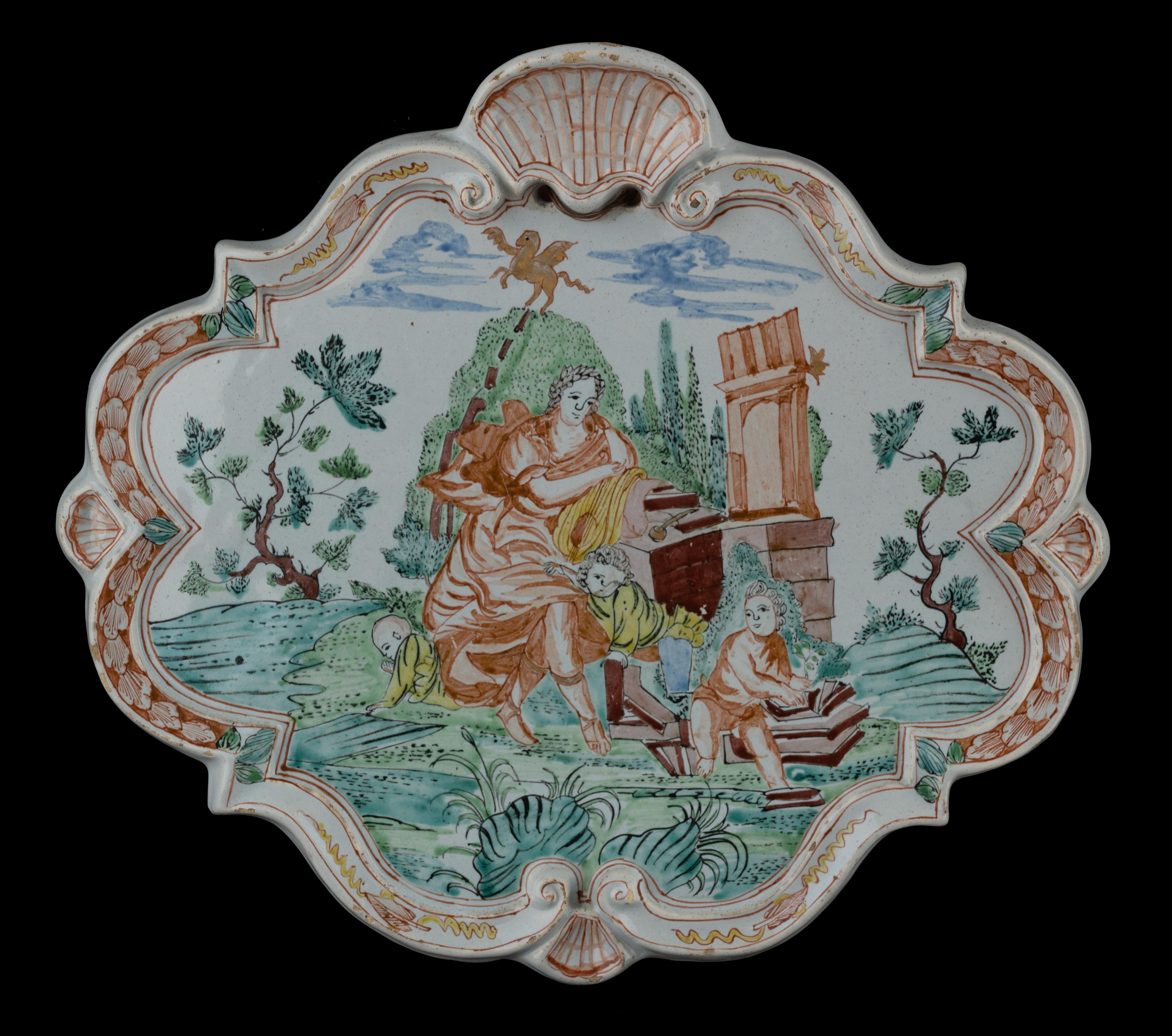 Polychrome plaque with an allegorical depiction. Delft, 1730-1750 

The lozenge-shaped plaque has a raised, accolade-shaped rim interrupted at the top by a large shell and at the bottom by a smaller shell. A shell is also modelled on both sides. The