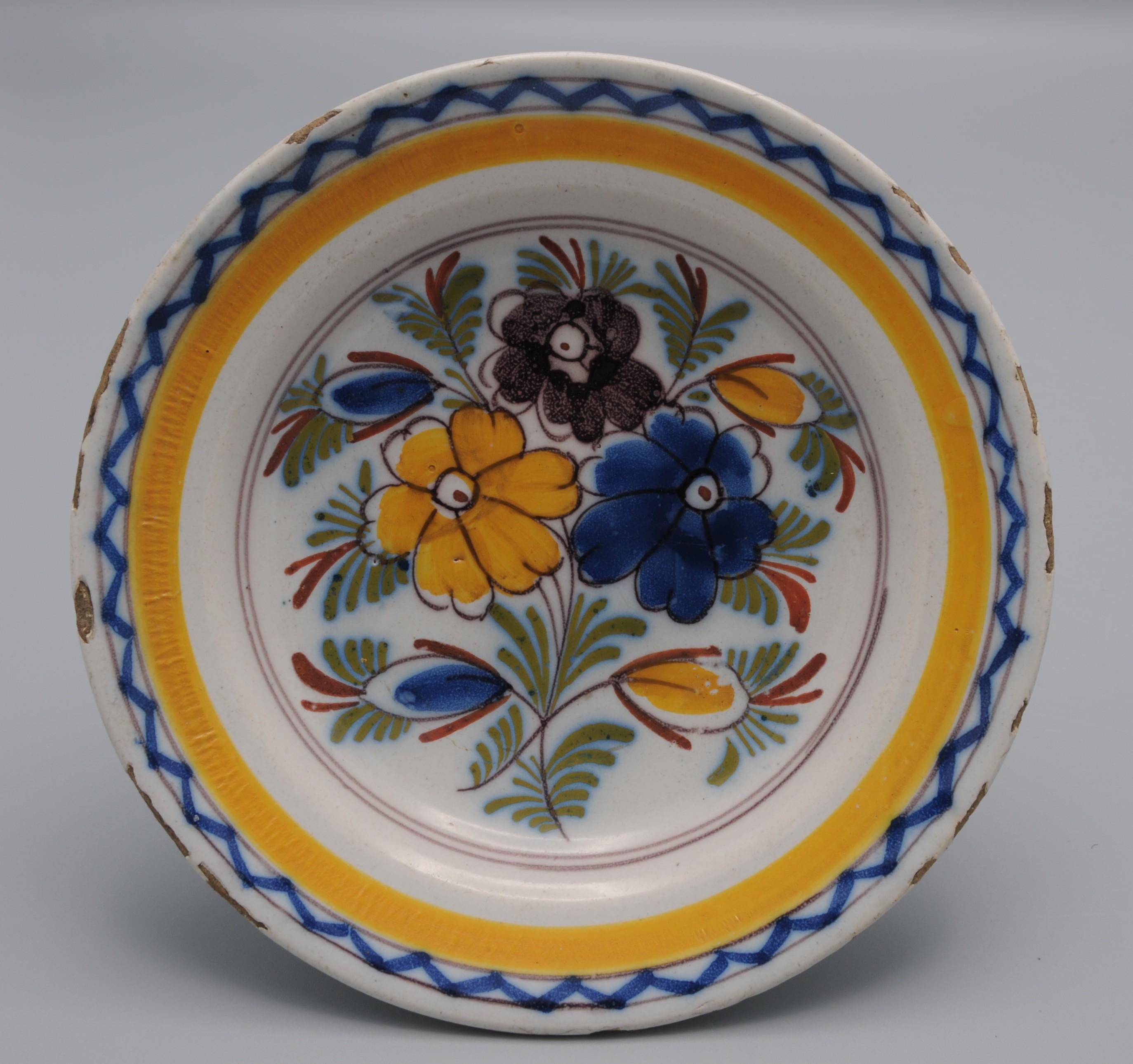 Assiette en faïence de Delft du début du 19e siècle avec une décoration florale polychrome en manganèse, jaune, bleu, vert et rouge de fer. 
Rare petit format. 
Bon état ; seule une légère usure habituelle du bord.