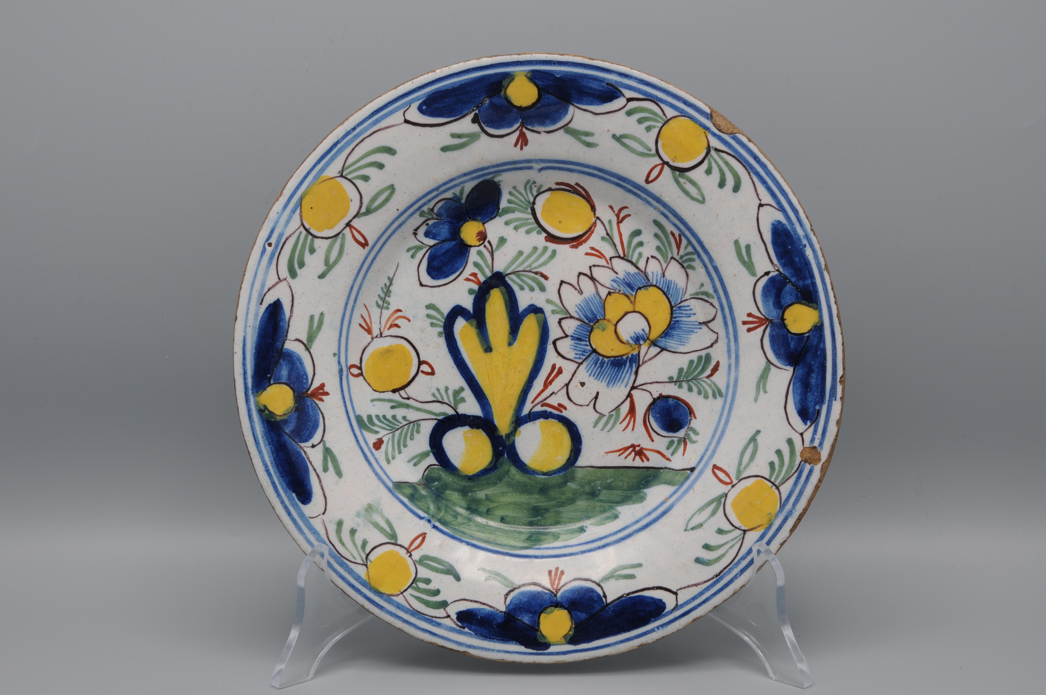  Plato de Delftware de principios del siglo XIX con decoración floral policromada en amarillo, azul, verde y rojo hierro. 

Buen estado; sólo un ligero desgaste habitual en el borde