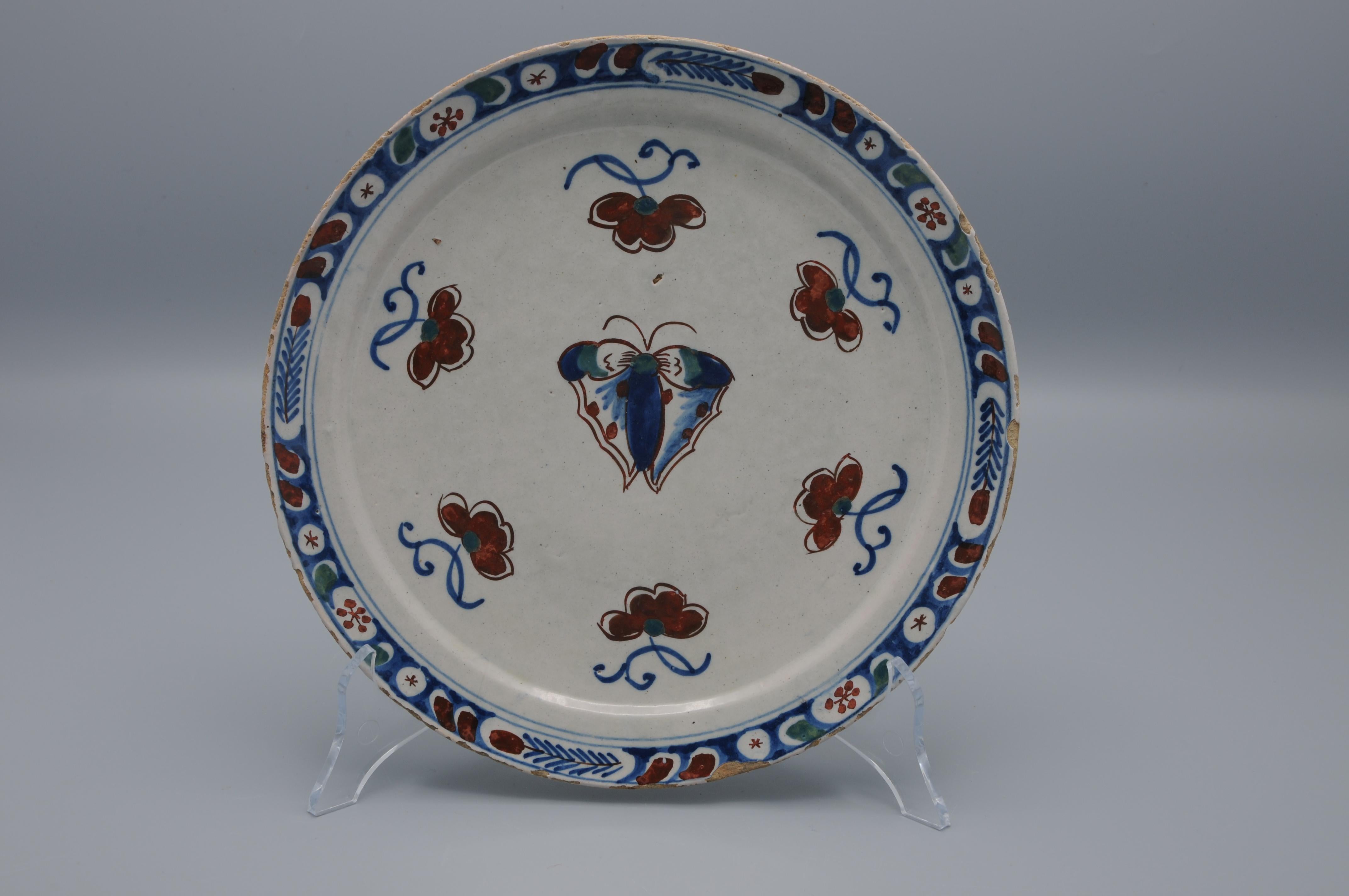 Rare assiette en faïence du début du 18e siècle avec un rare décor de papillon en bleu et rouge de fer.

non marqué mais d'une beauté étonnante. 
Bonne qualité de la peinture
Bon état ; seule une légère usure habituelle du bord.
