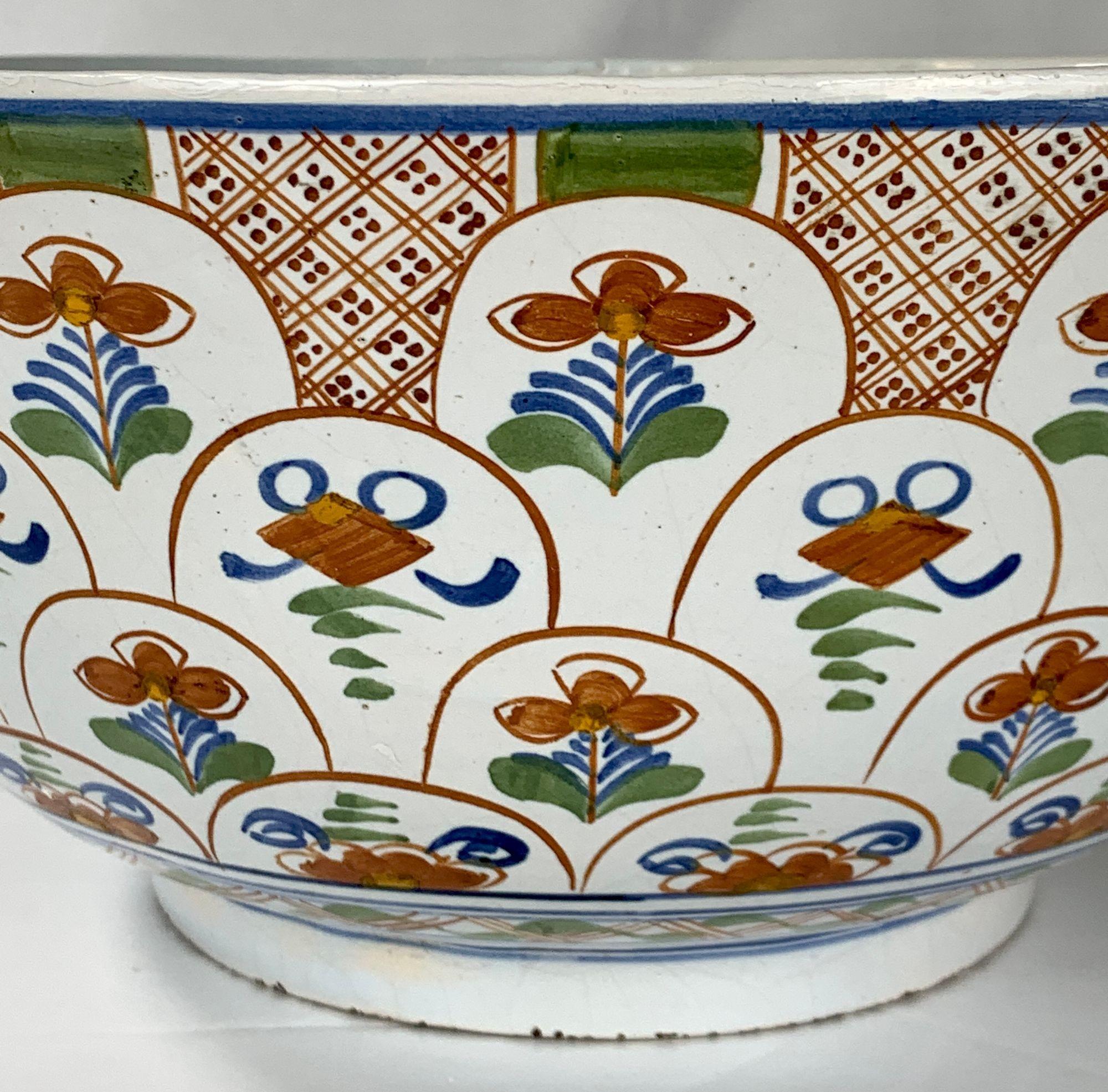 This 18th-century Dutch Delft punch bowl is hand-painted in vibrant polychrome colors of orange, green, and cobalt blue.
Dozens of individual green-leaved orange tulips seem to rise from the base of the bowl.
The effect is beautiful!
Panels of