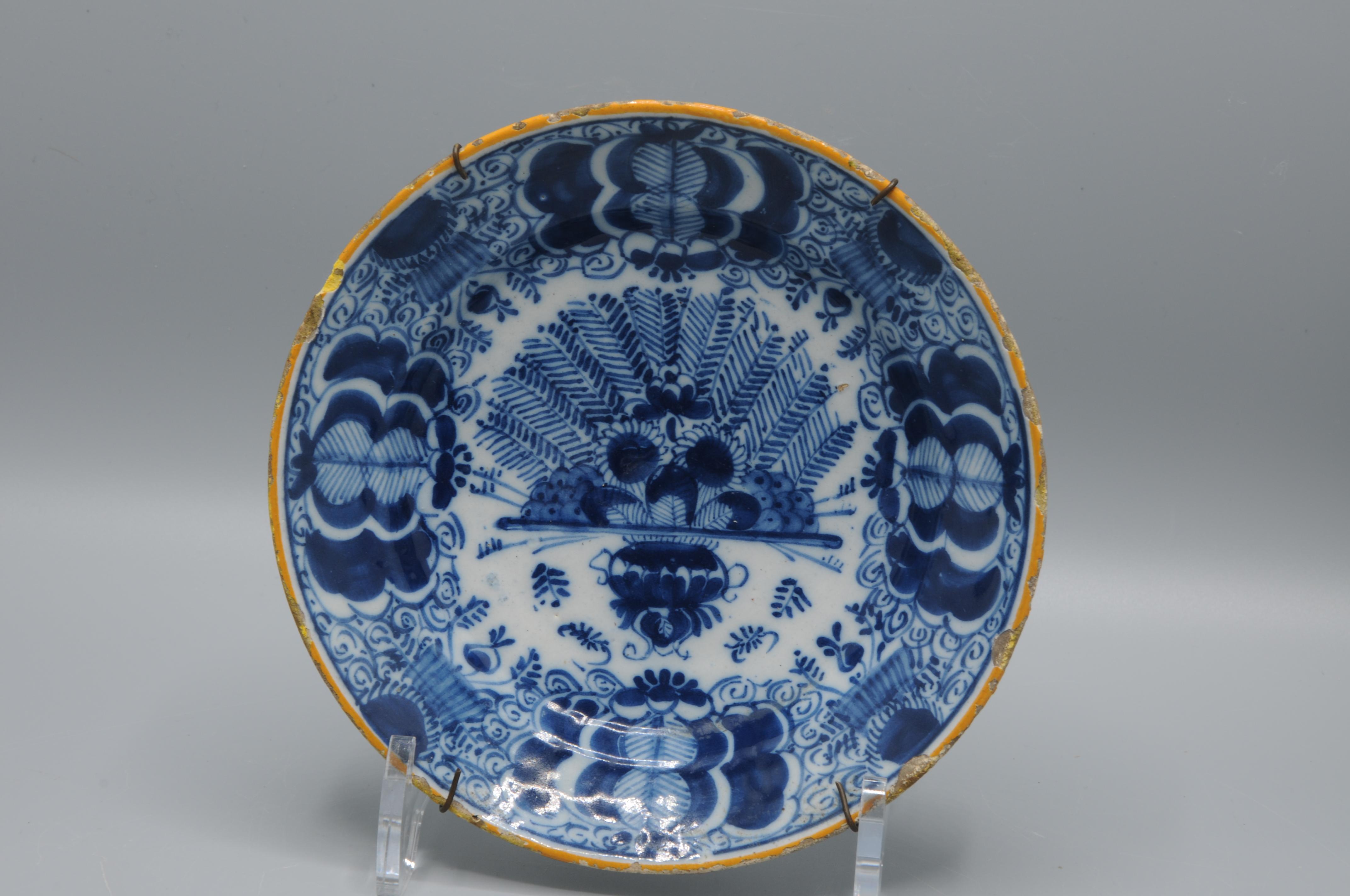 Rare smaller sized Dutch Delft blue and white 'Peacock' plate, late 18th century, with ochre rim, the centre decorated in cobalt with an vase containing an arrangement of peacock feathers and flowers. The rim decorated with stylized flower heads