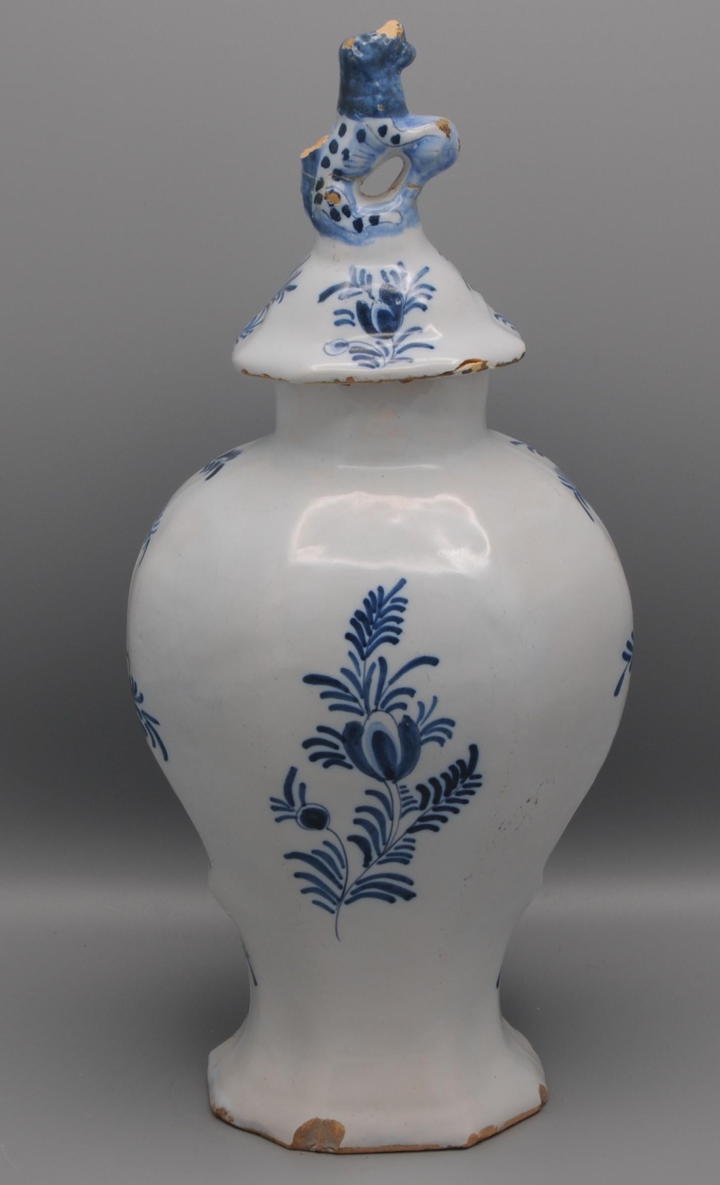 Late 18th century Blue Delftware lidded vase with central decoration of a flower bouquet in a cartouche. 
Finial with foo dog alike creature. 

Marked on underside: LPK for 