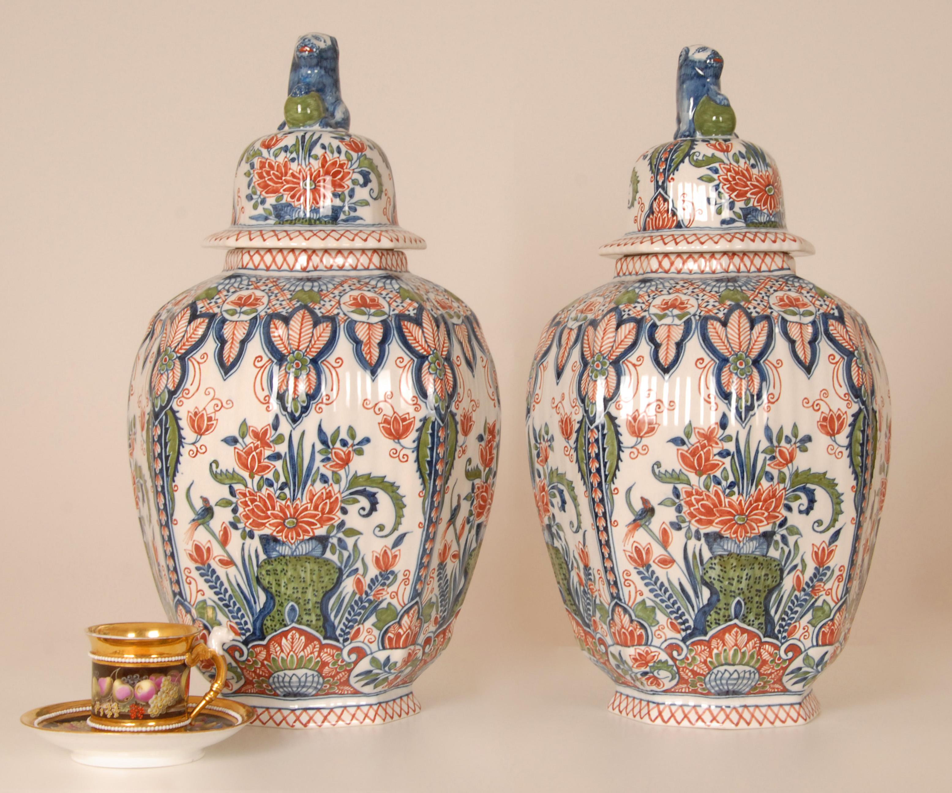 Hohe Vasen aus Delft, niederländische Tinglasur-Keramik mit polychromem Dekor. 
Das Set besteht aus 2 hohen Vasen mit Deckel 
Herkunft: Die Niederlande 1940er Jahre
Farben: Grün, Eisenrot, Blau, Weiß (chinesische famille verte Farben oder
