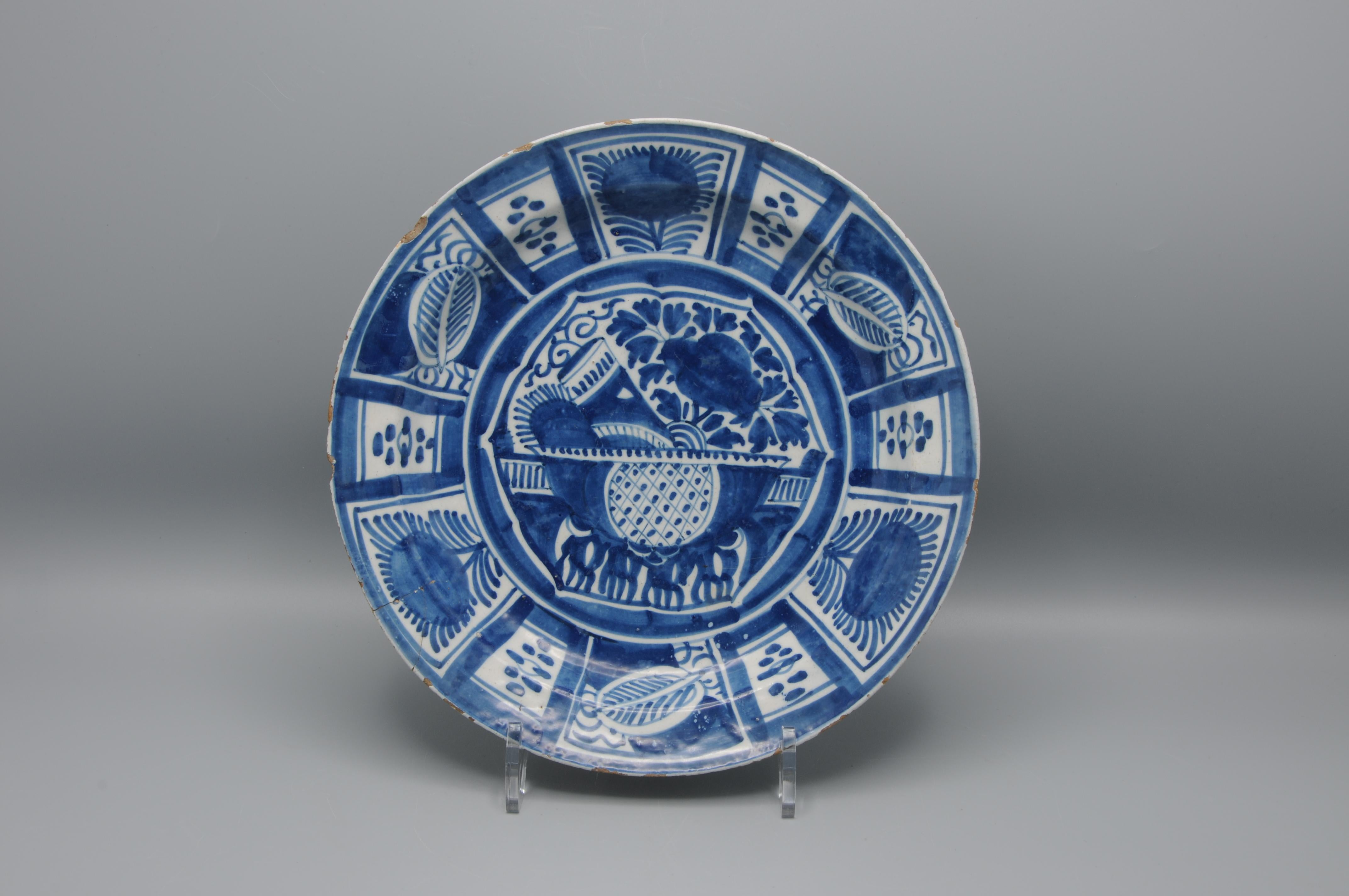 Grand plat et petit chargeur en bleu et blanc de Whiting, 18e siècle. La réserve centrale représente un vase de fleurs, entouré d'une large bordure de panneaux floraux et géométriques alternés. Le design reflète l'influence de la porcelaine kraak de