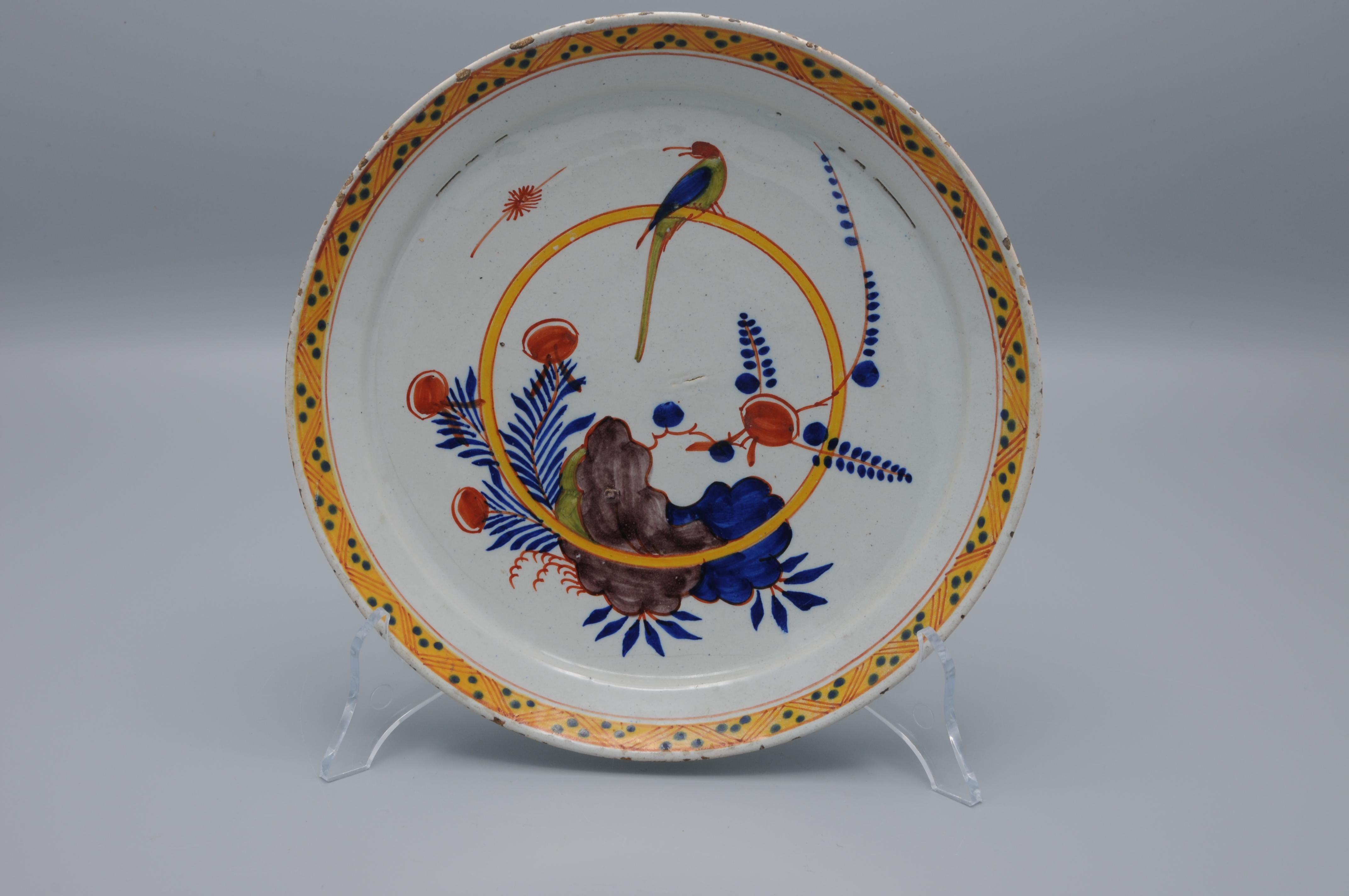 Un chargeur polychrome avec un perroquet perché sur un anneau au centre, avec d'intéressants éléments de paysage asymétriques montrant une base dans le design du début du 18ème siècle. La simplicité de la composition et le bord avec sa bordure