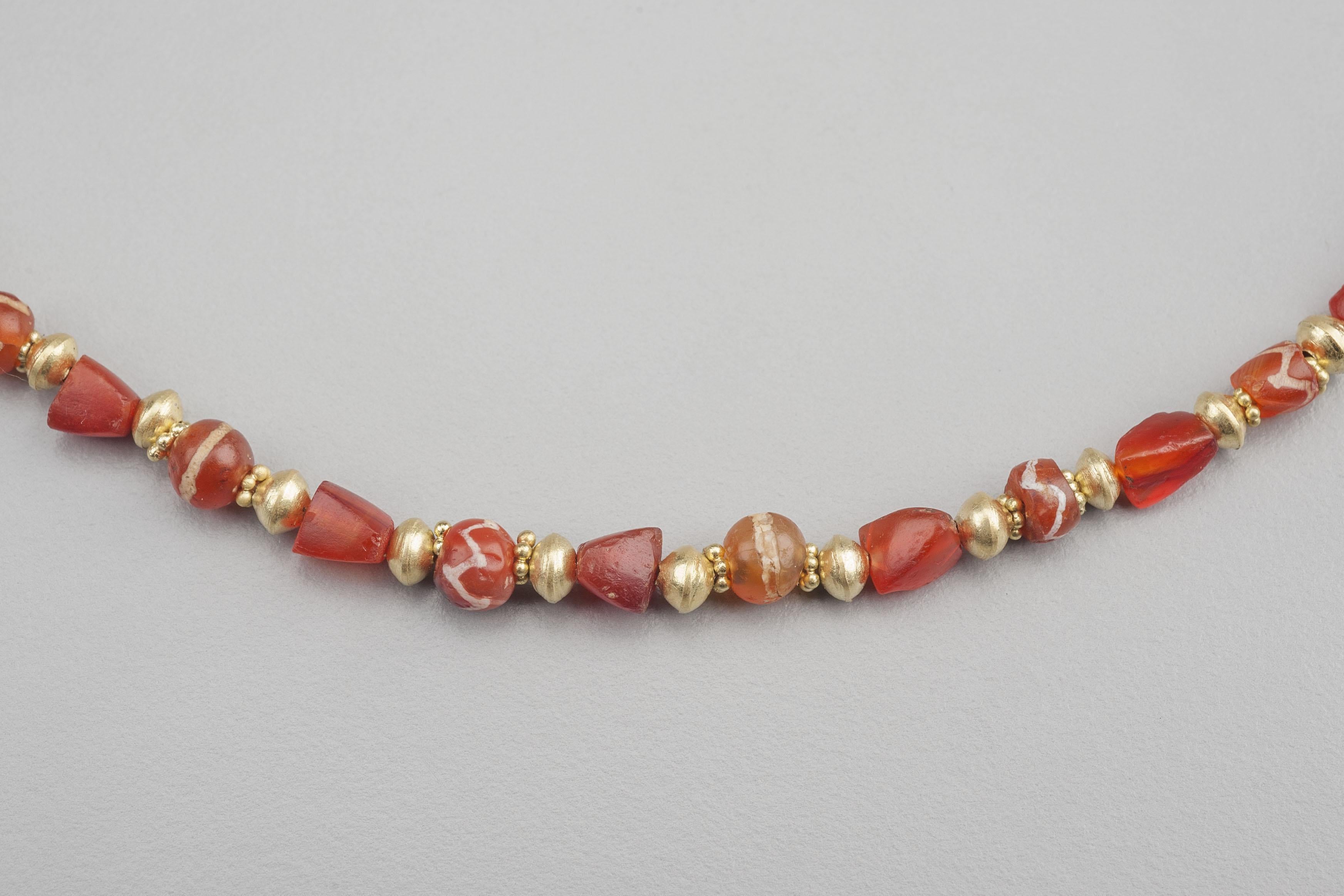 Fifty-nine carnelian beads alternating with fifty-eight round 20k gold beads. Of the carnelian beads, twenty-nine are artificially patterned round beads, (called “etched”), and thirty are undecorated carnelian beads with alternating trapezoidal