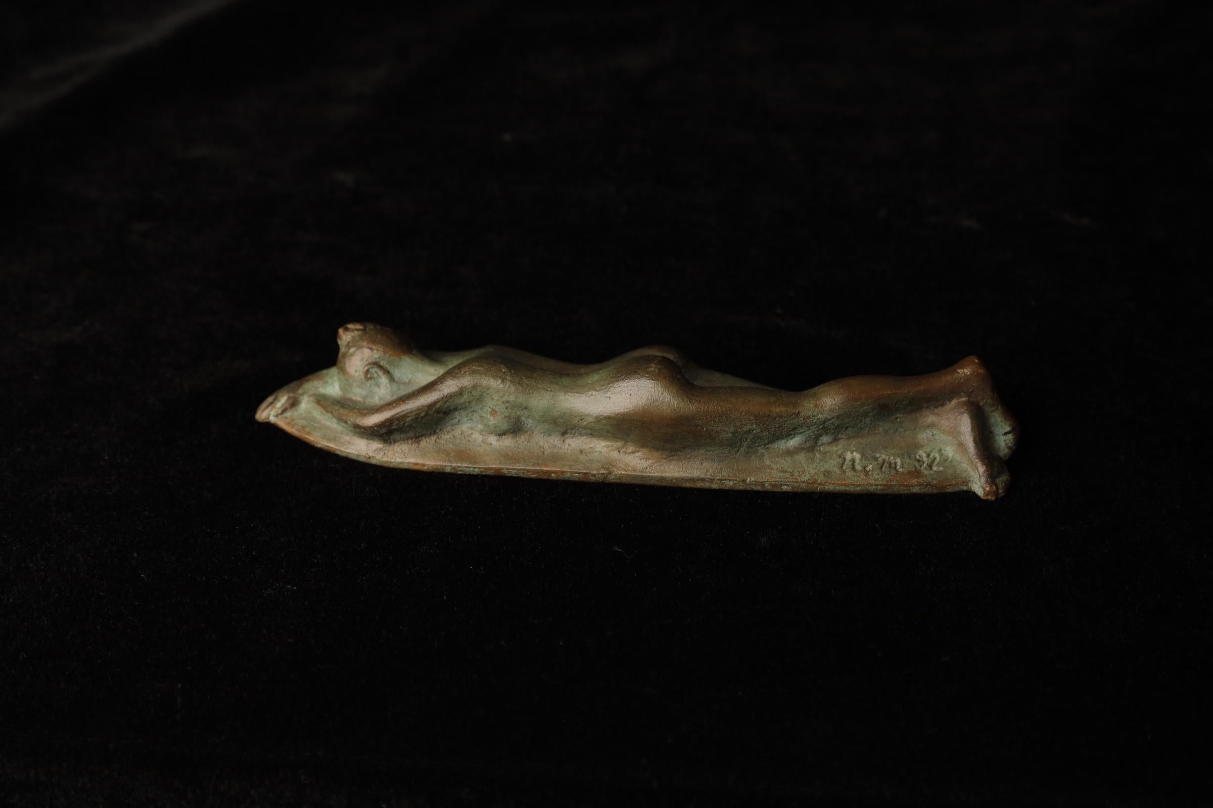 This elegant bronze sculpture by Japanese artist Nobuo Murakoshi depicts a reclining female figure with smooth, organic forms. The surface of the bronze has developed a natural patina, giving the piece a unique character and depth. The minimalist