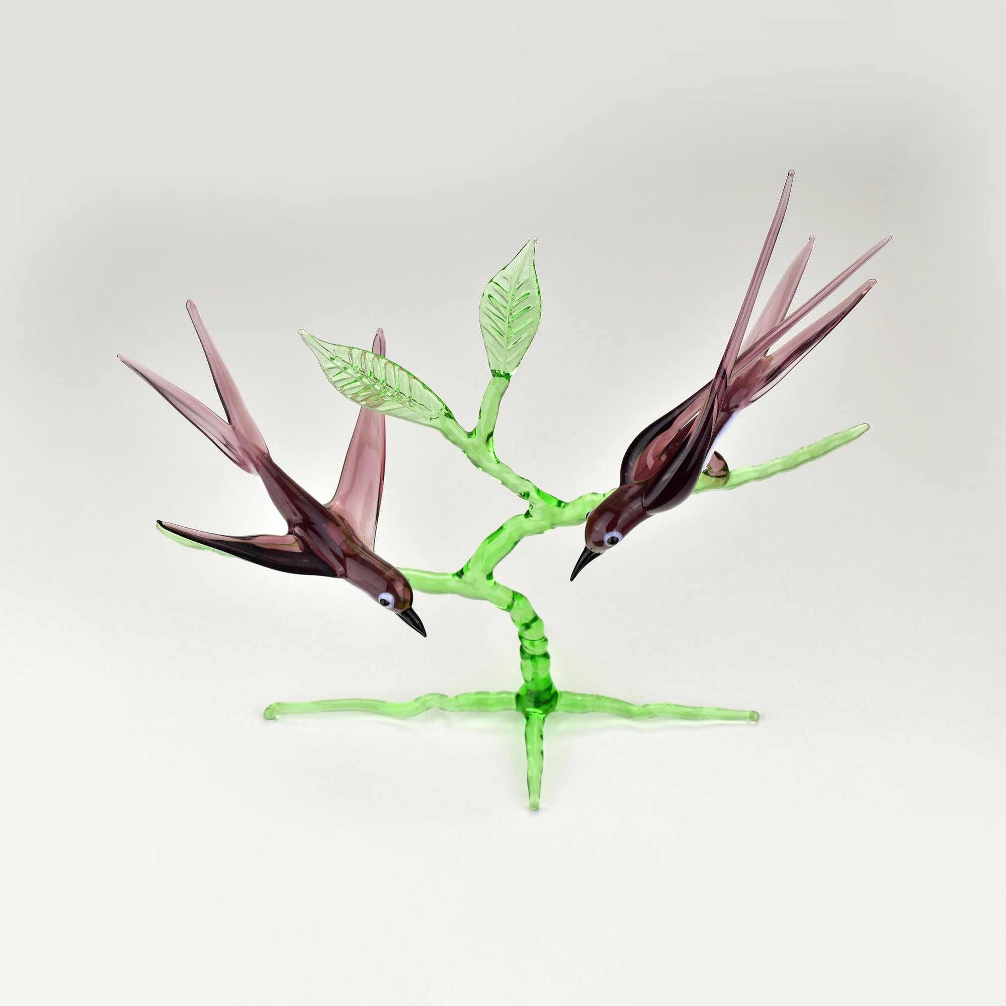 Cette exquise sculpture en verre d'art de Murano du milieu du siècle capture la beauté délicate de deux hirondelles perchées sur une branche d'un vert éclatant. 

Fabriqués à la main par des experts, les oiseaux ont un corps translucide de couleur