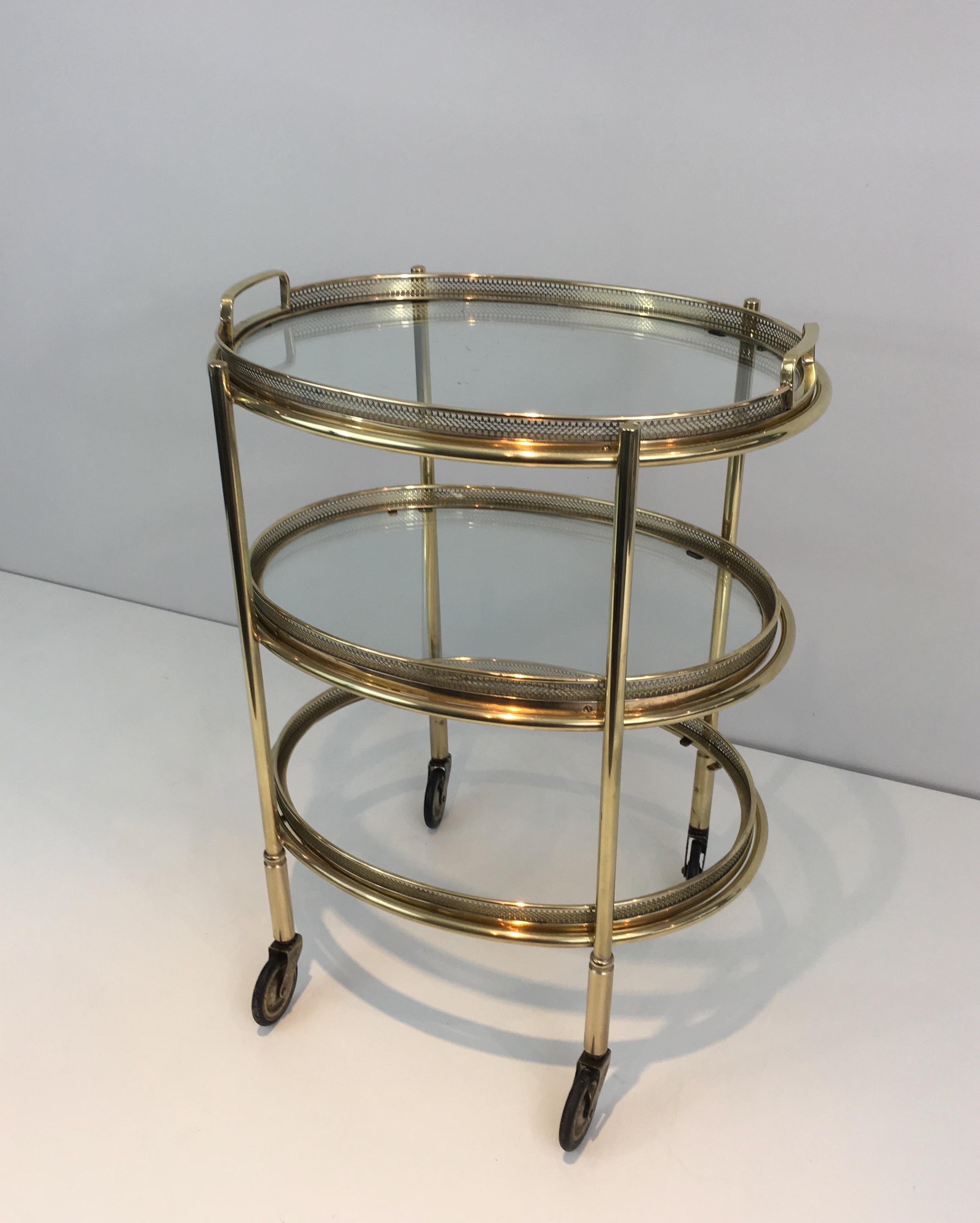 This delicate neoclassical oval trolley is made of brass. It has 3 removable glass shelves surrounded by a brass tray. This is a French work, in the style of famous French designer Maison Jansen, circa 1940.