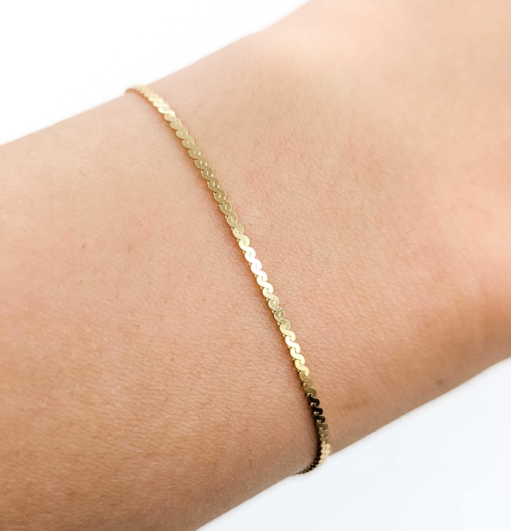 A timeless S-link bracelet crafted in 14k yellow gold, featuring a smooth, fluid design that catches the light beautifully. This elegant chain measures 1.25mm wide and 7 inches long, secured with a spring ring clasp for classic styling and easy